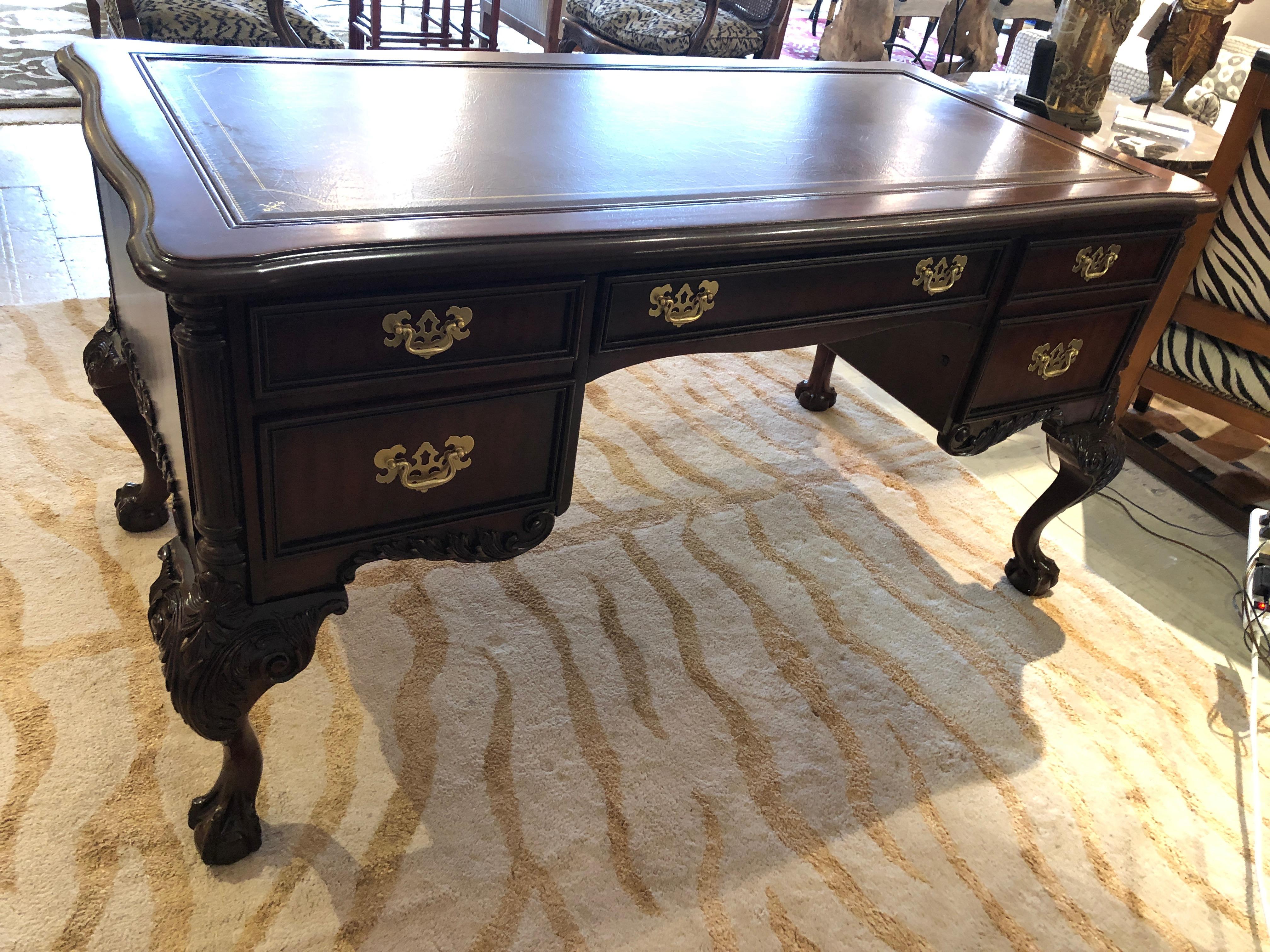 A luxurious carved mahogany executive desk having brown tooled leather top with gilded decoration, 4 smoothly operating drawers including one on the bottom right for hanging files. The ornate cabriole legs with ball and claw feet are especially