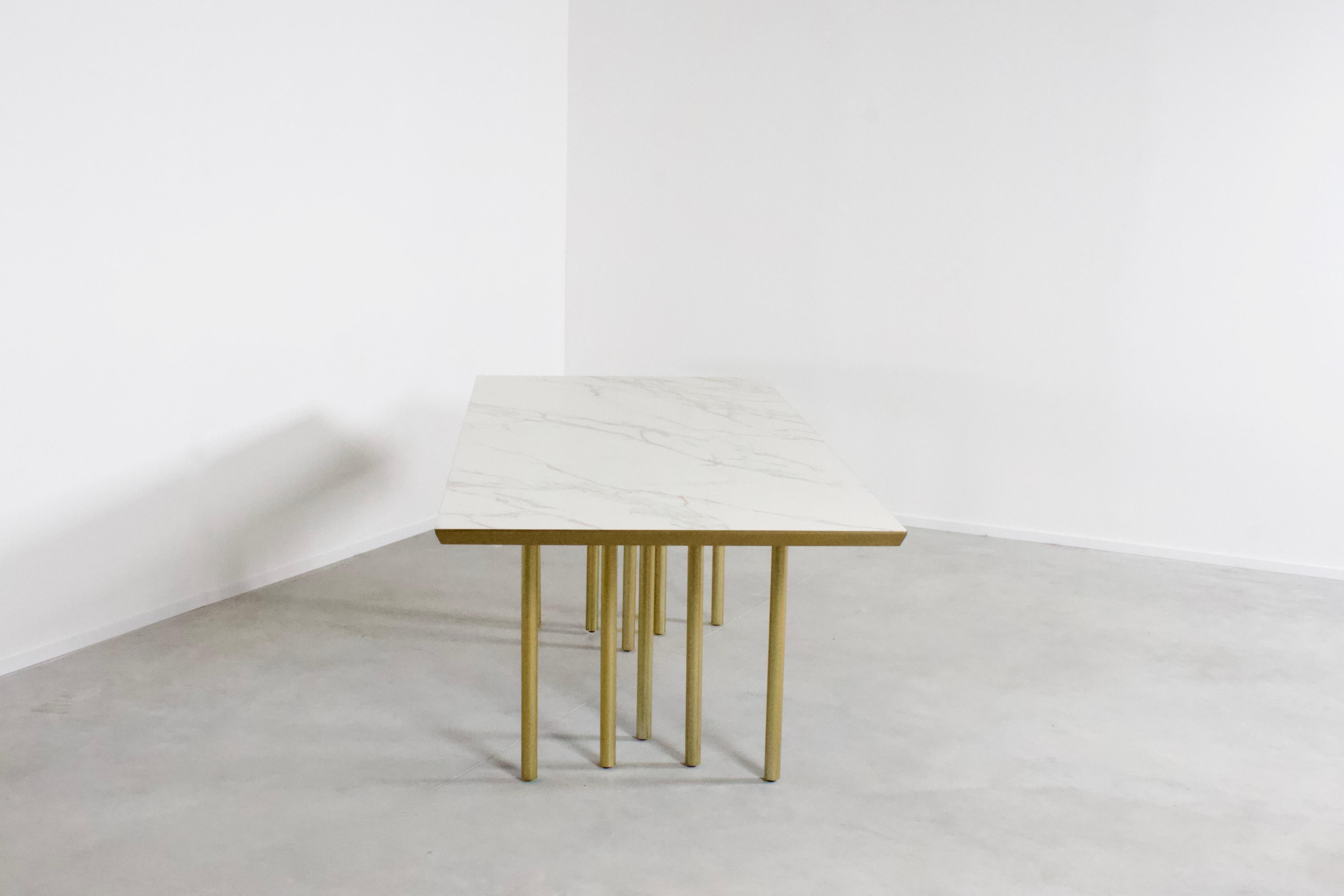 Beautiful contemporary 'Alta Ara' dining table. 

Designed by Bas Merckx 

This table is equipped with ten feet in a satin finished brass. 

The top is made from a mat ceramic with a Carrara marble look and has been finished with a brass rim