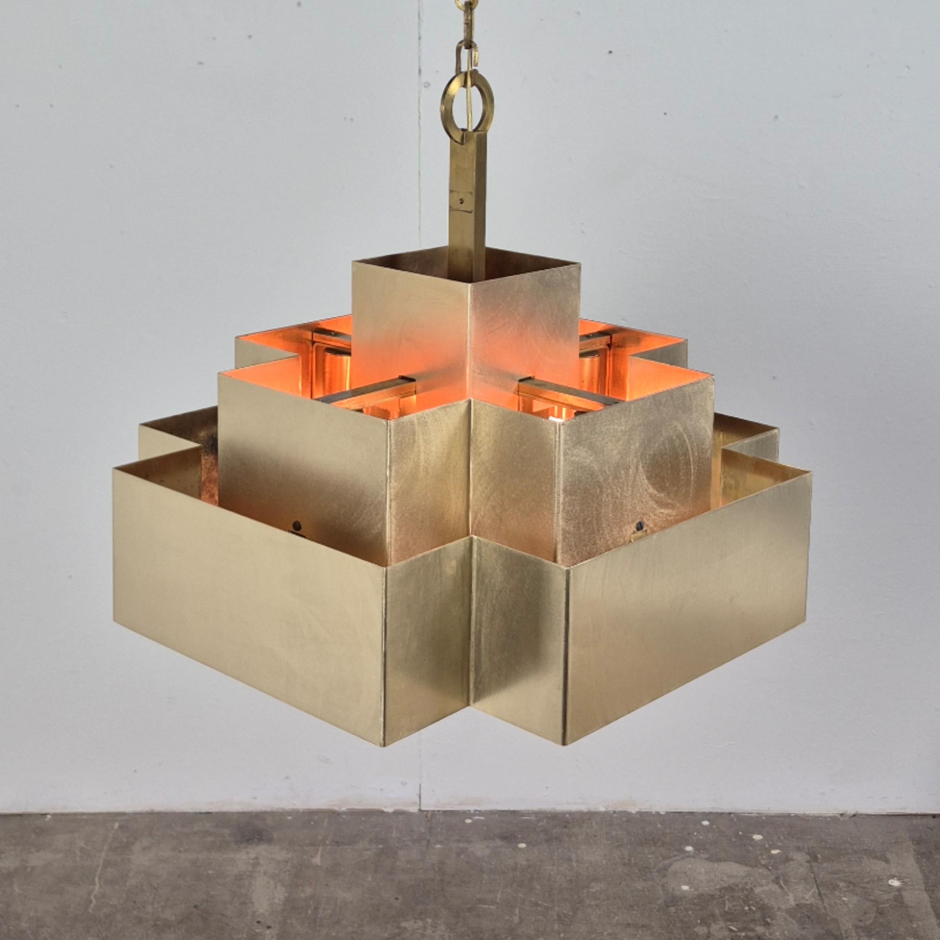 This hand made cubist style chandelier is made entirely from copper.
The shade is made up of two pieces. The lower half is suspended under the upper part with hooks and brackets.
Inside there are 5 sockets. One on each corner and one in the center.