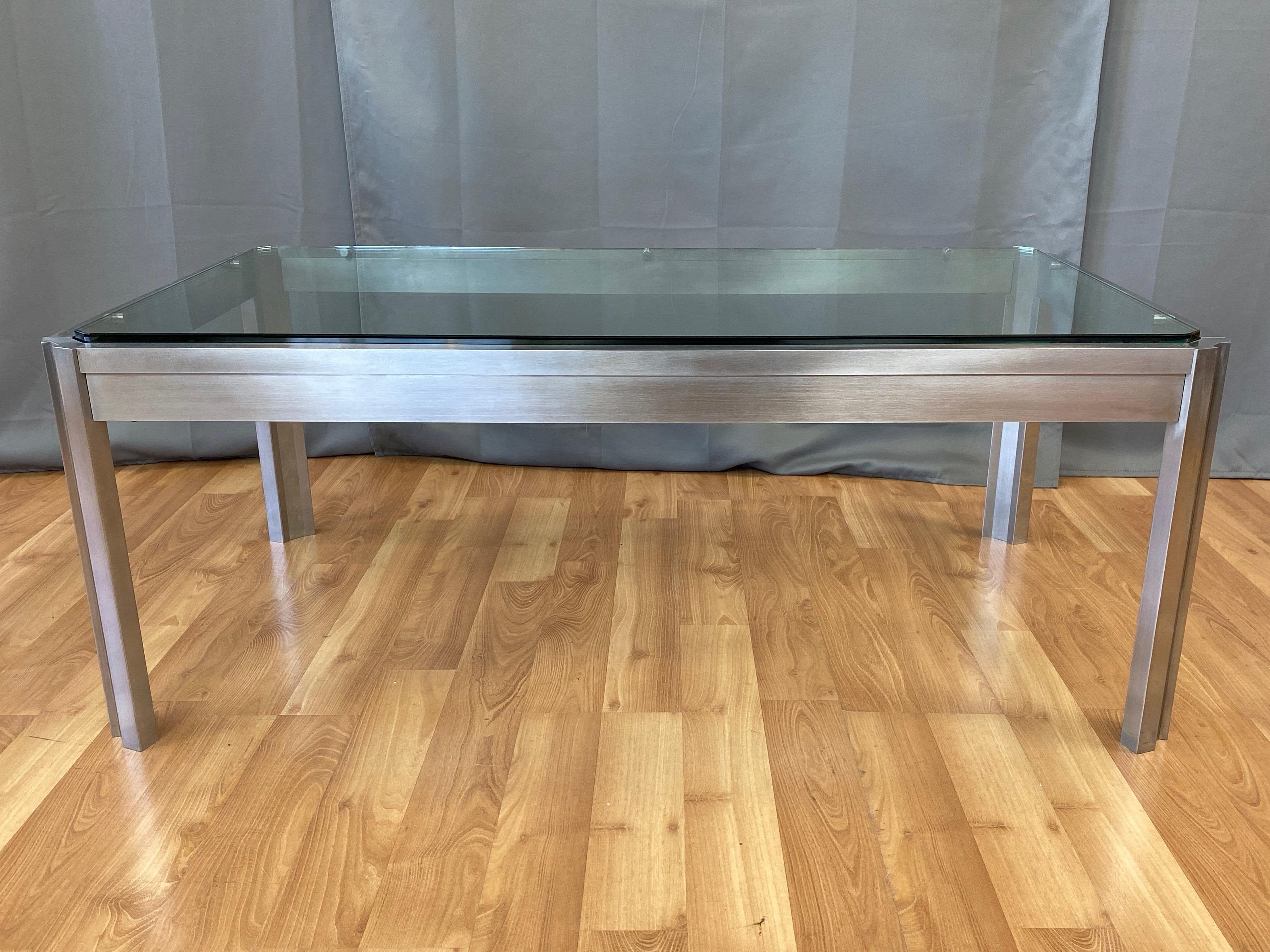 A substantial and unique 1970s brushed stainless steel and glass coffee table from the estate of Henri and Tomoye Takahashi.

Large and heavy custom fabricated frame of exactingly machined and assembled solid stainless steel, with channeled legs and