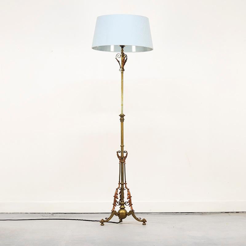 Elegante lampada da terra a stelo realizzata in ottone pesante con ornamenti di foglie d'acanto in rame rosso. La lampada è ricca di dettagli e poggia sulle classiche zampe di un leone. Originariamente una lampada a gas, è stata convertita in