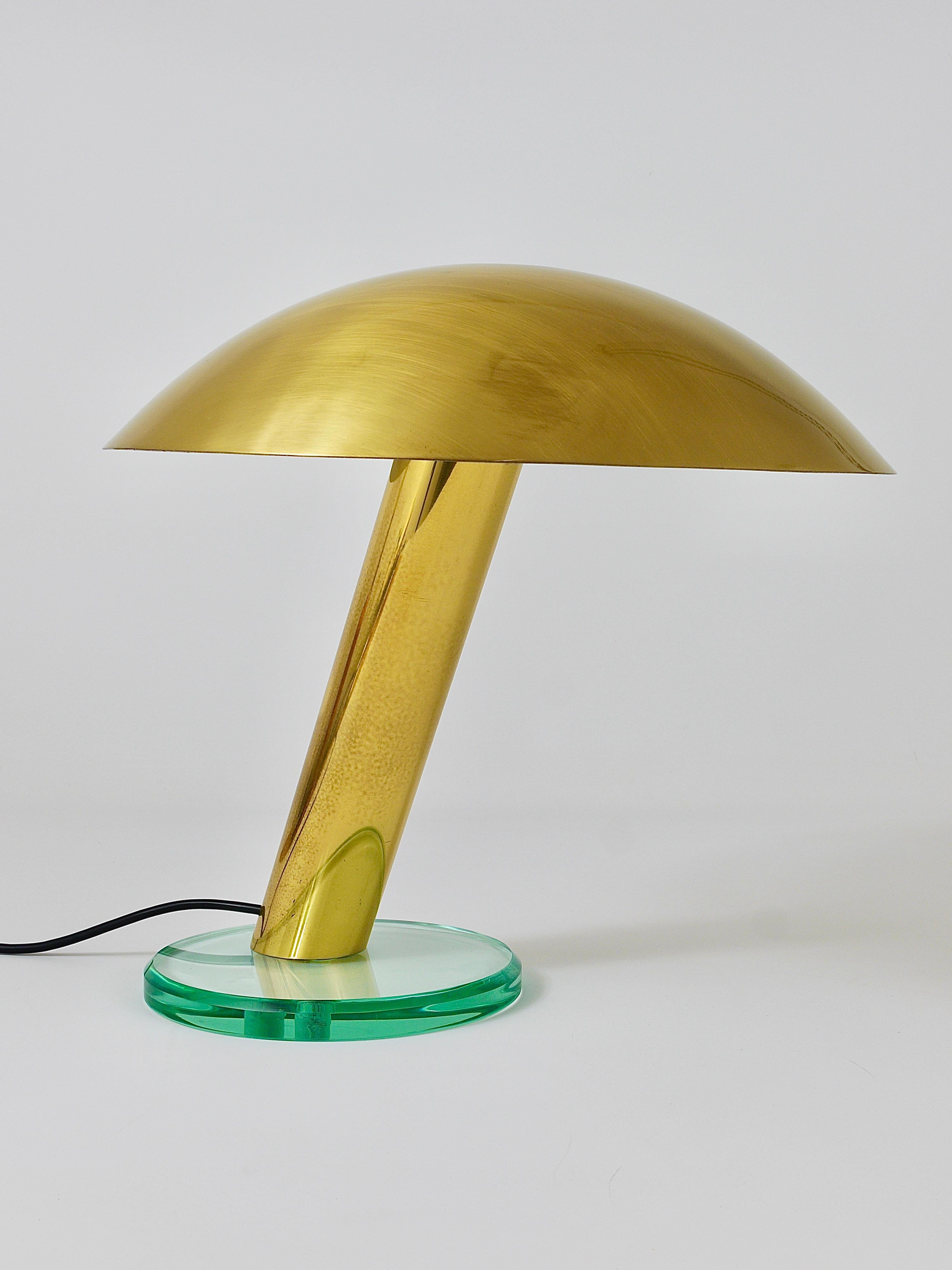 An outstanding Italian midcentury desk or side lamp from the 1960s. In the style of Max Ingrand / Fontana Arte. This beautiful lamp is made of polished brass and has an inclined neck, a thick, solid, glass base and a round lampshade with white