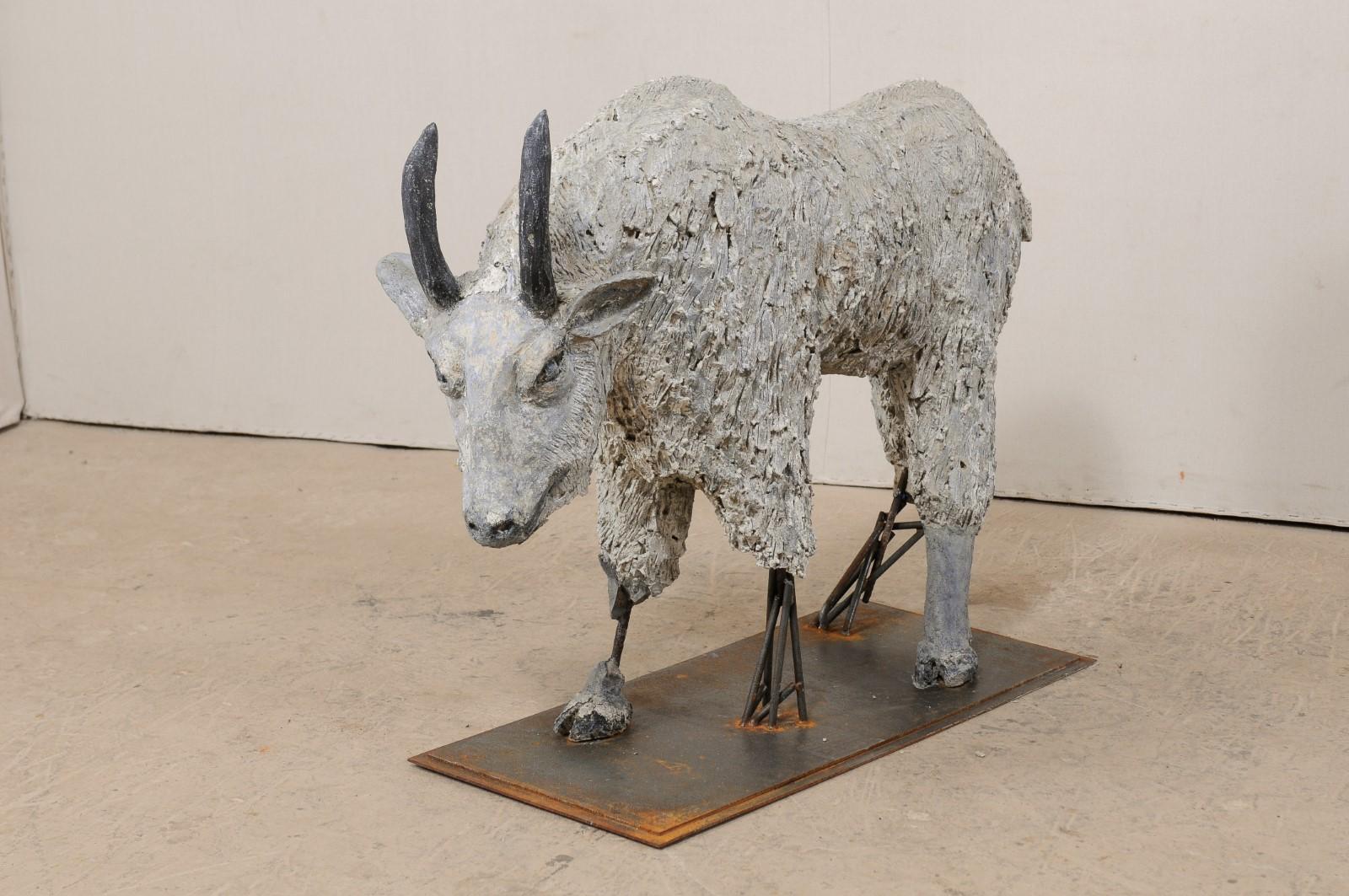 An impressive French mountain goat sculpture from the early to mid 20th century. This French folk-art concrete sculpture features a mountain goat carved with a heavily textured coat, lowered grazing head stance, with horned head and hump at