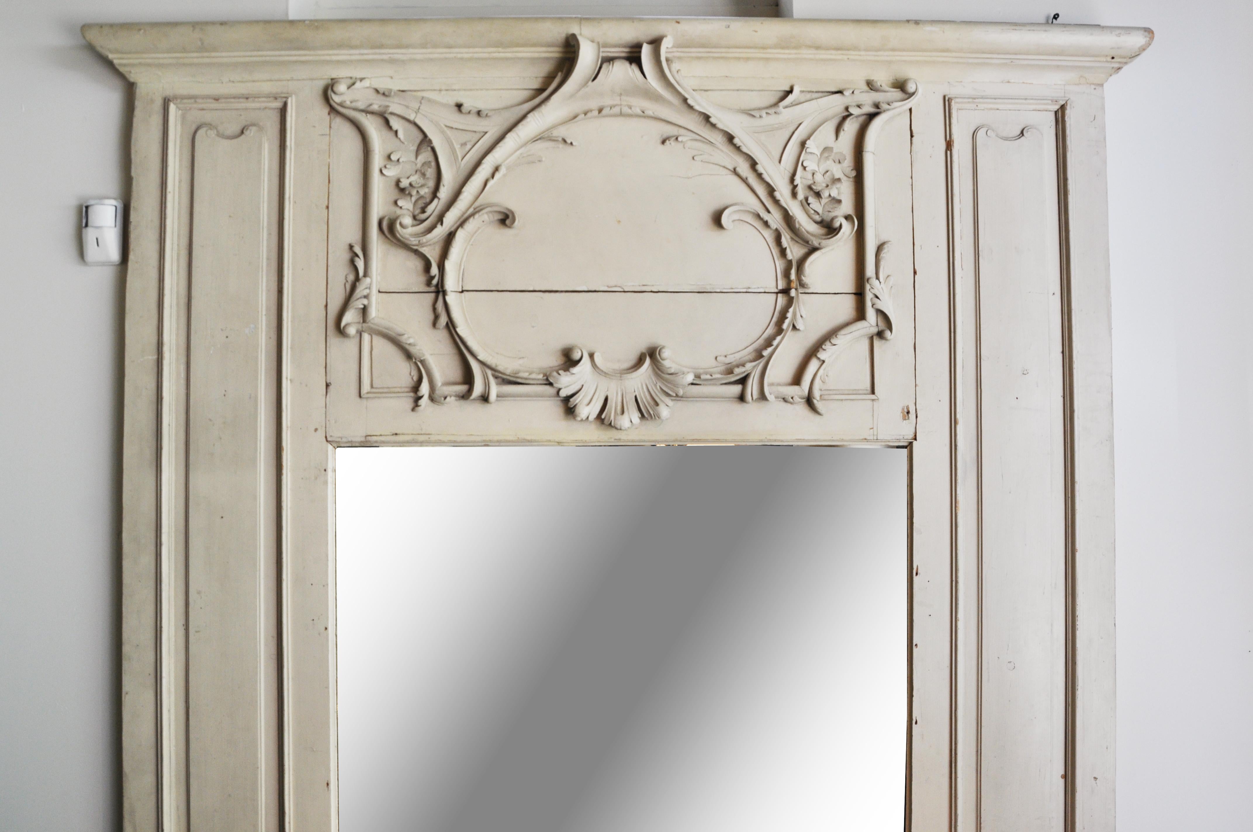 This elegant wall mirror is from France and was made from wood and glass, circa 19th century. This large and well-carved mirror frame was once part of the architecture of a prominent room such as a dining room or salon. The flat panels are fir or