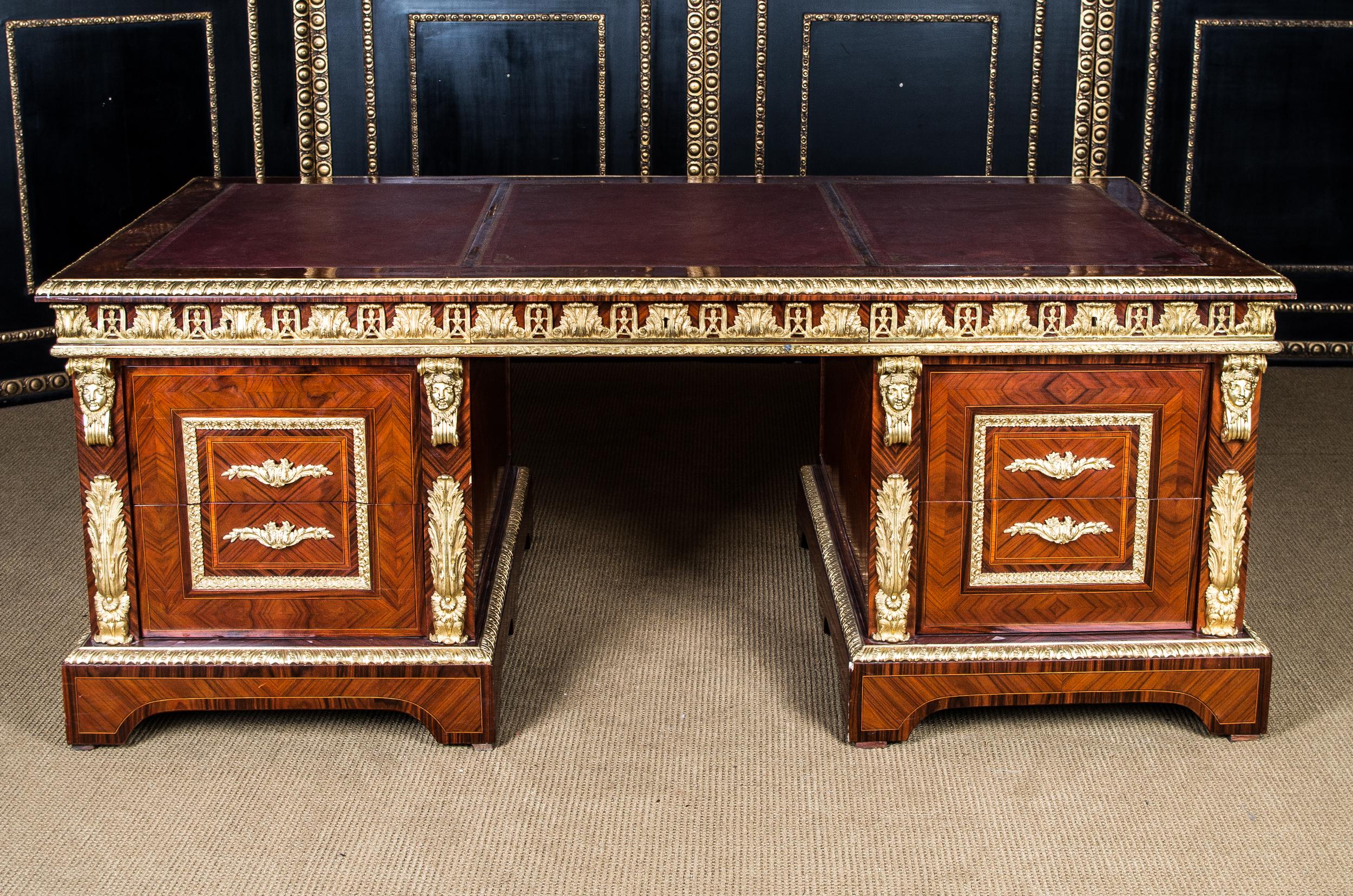 Royal palisander and tulip wood on softwood. Three-part straight frame base. Slightly protruding, broadly framed writing surface, inlaid with gold embossed leather surface, including three drawers of different sizes with decorated frieze of acanthus