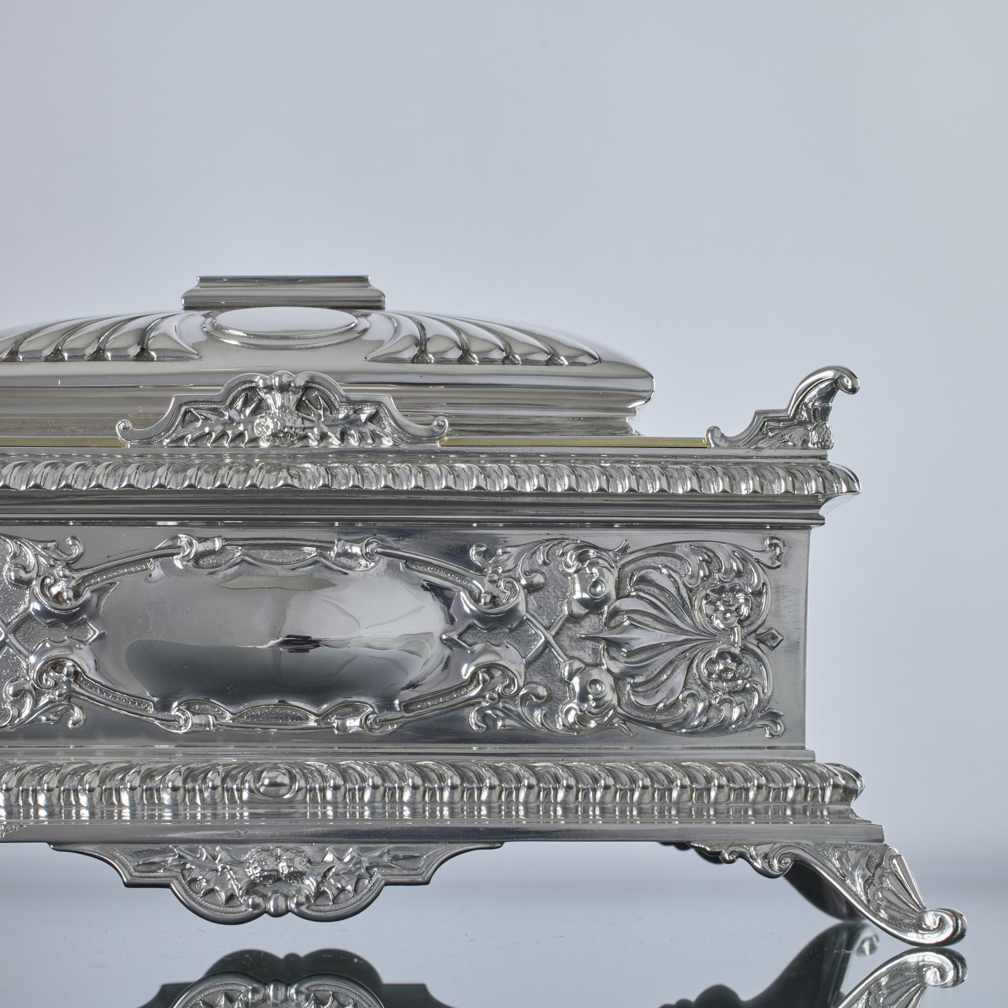 Large and decorative antique silver jewellery box of superb quality and lined with green velvet. The exterior has cast and applied supports and corners, domed central panel on the lid, slant gadroon borders and embossed panels. There are applied