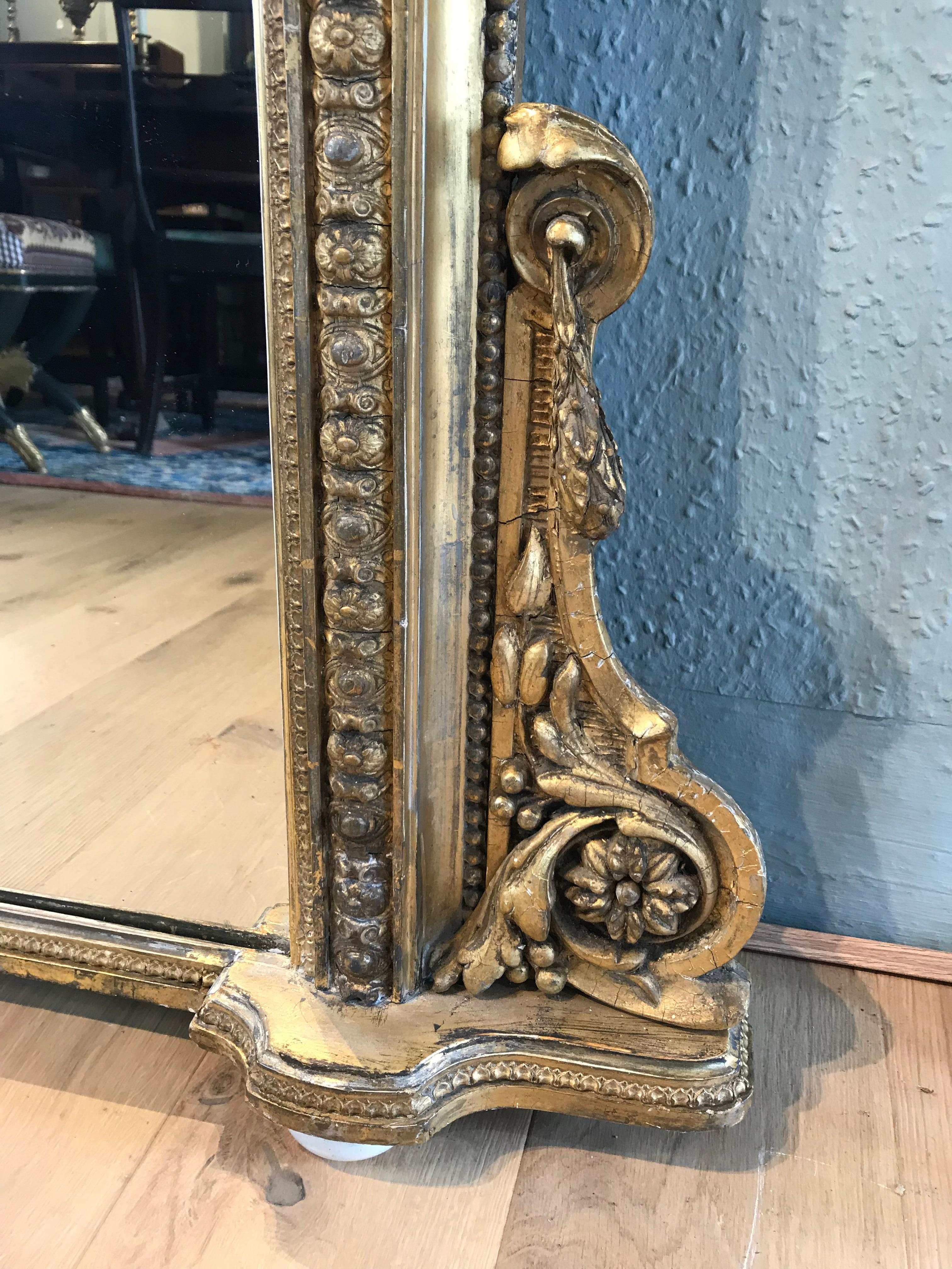 An Impressive 19th-century gilt arched top overmantel mirror set on porcelain bun feet. This stunning overmantel is in very good condition, with beautifully detailed worn through gilding. The mirror has an ornate moulded flower and scroll inner