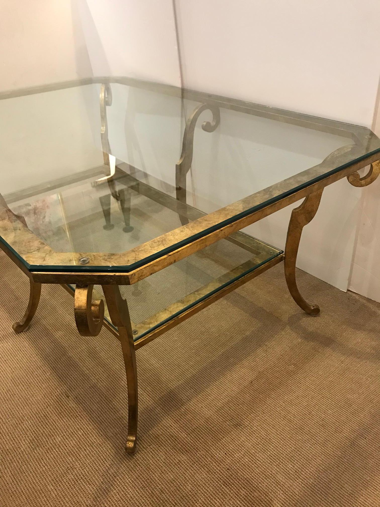 Gorgeous large and heavy gilt iron two-tier coffee table having squared off edges and curlicue curved legs.
Bottom tier 41” W x 20.5” D x 9.75” H.