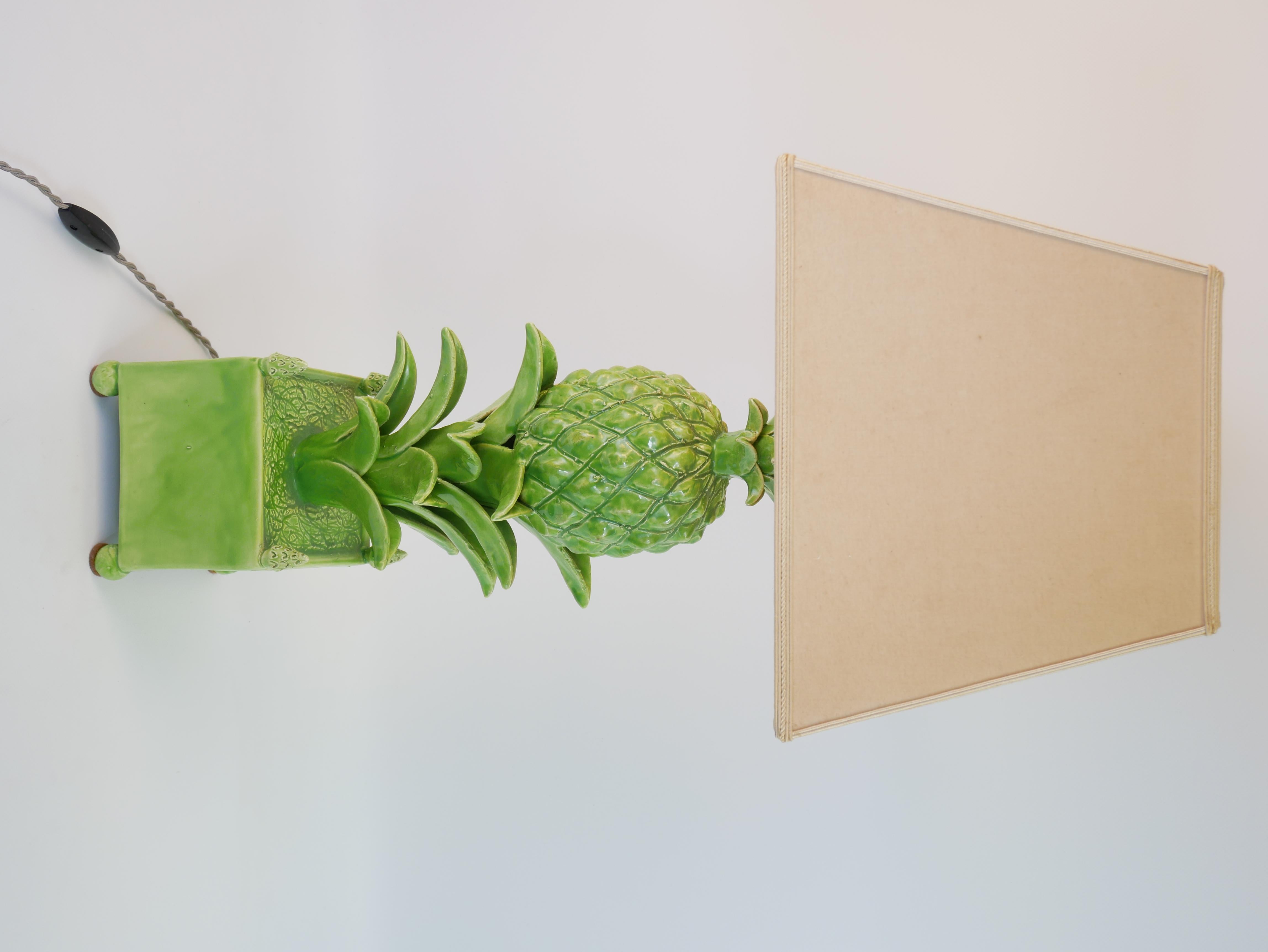 Diese elegante Keramiklampe von Jean Roger ist ein beeindruckendes Beispiel für die Meisterschaft des Künstlers in der dekorativen Beleuchtung. Inspiriert von tropischen Motiven zeigt die Lampe eine skulpturale Ananas, die auf einem üppigen