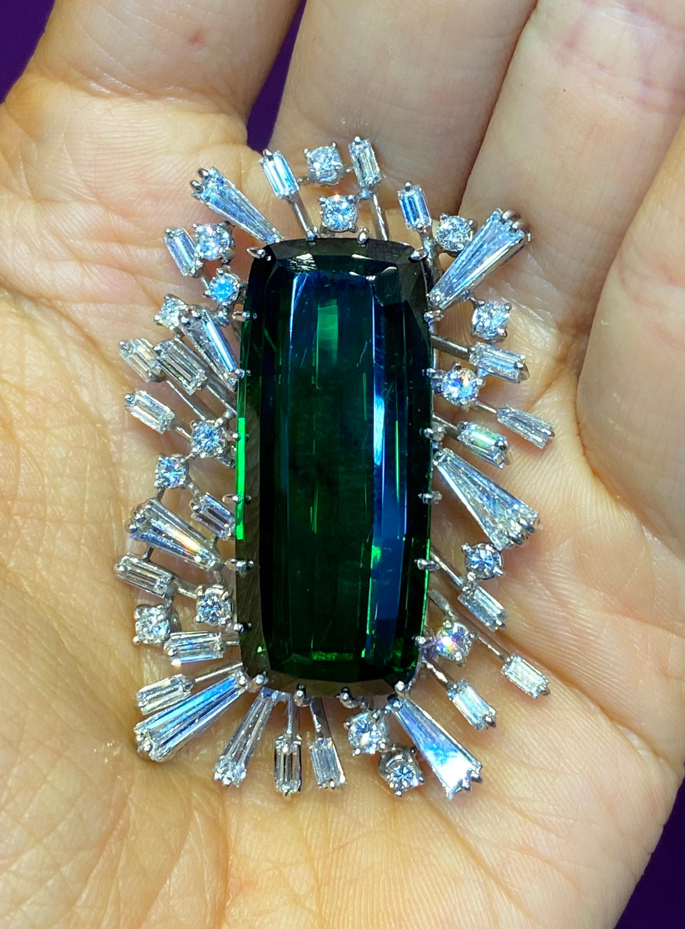 Tourmaline & Diamond Brooch
Mounted in Platinum
Approximate weights:
Emerald cut Green tourmaline 39.62 carat,
27 square shaped diamonds 3.90 carats
16 round diamonds 1.10 carats

Measurements: 1.75