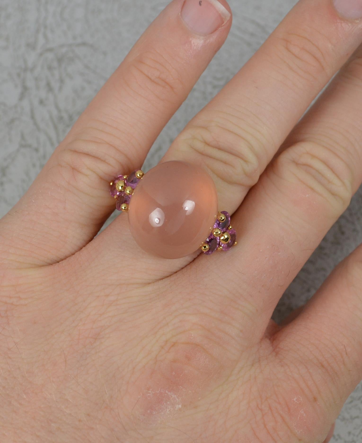 A stunning quality cluster statement ring.
Solid and heavy 18 carat yellow gold example.
Set with a large, oval shaped, cabochon rose quartz to centre. 16mm x 18mm.  Complete with three round cut vivid pink sapphires to each side. 2.5cts of