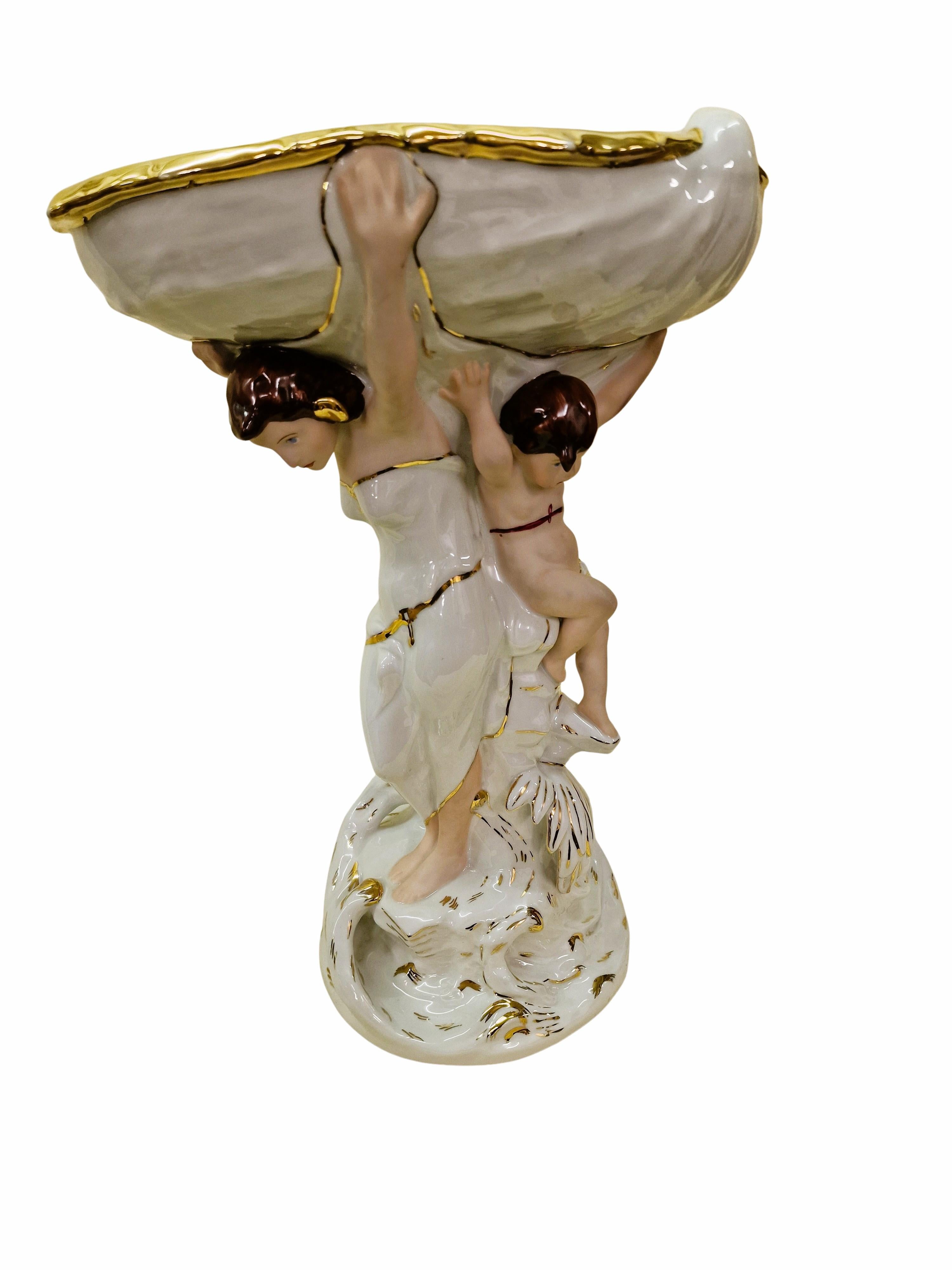 This monumental centerpiece is a work by the famous Bohemian company Royal Dux, made of porcelain, in Art Nouveau style carried out around the 1940/50. 

The object is a masterpiece, it is incredibly difficult to make a complicated porcelain figure