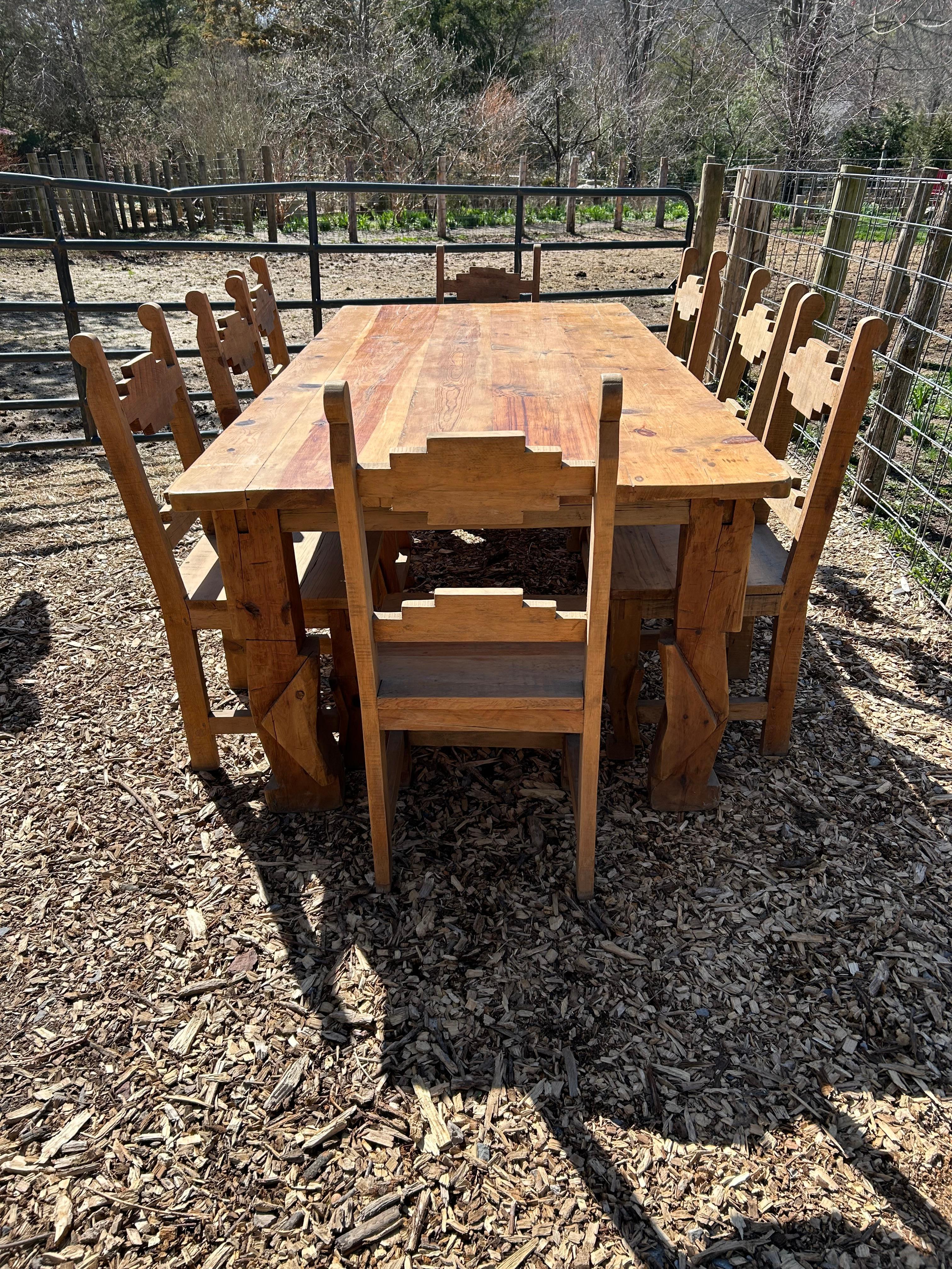 Impressive large hand made heavy pine rustic farm table having sculpted geometric chunky legs and beautiful natural honey color with nice grain and knots on top. 
Apron height 26.5”

8 matching rustic pine dining side chairs are available and