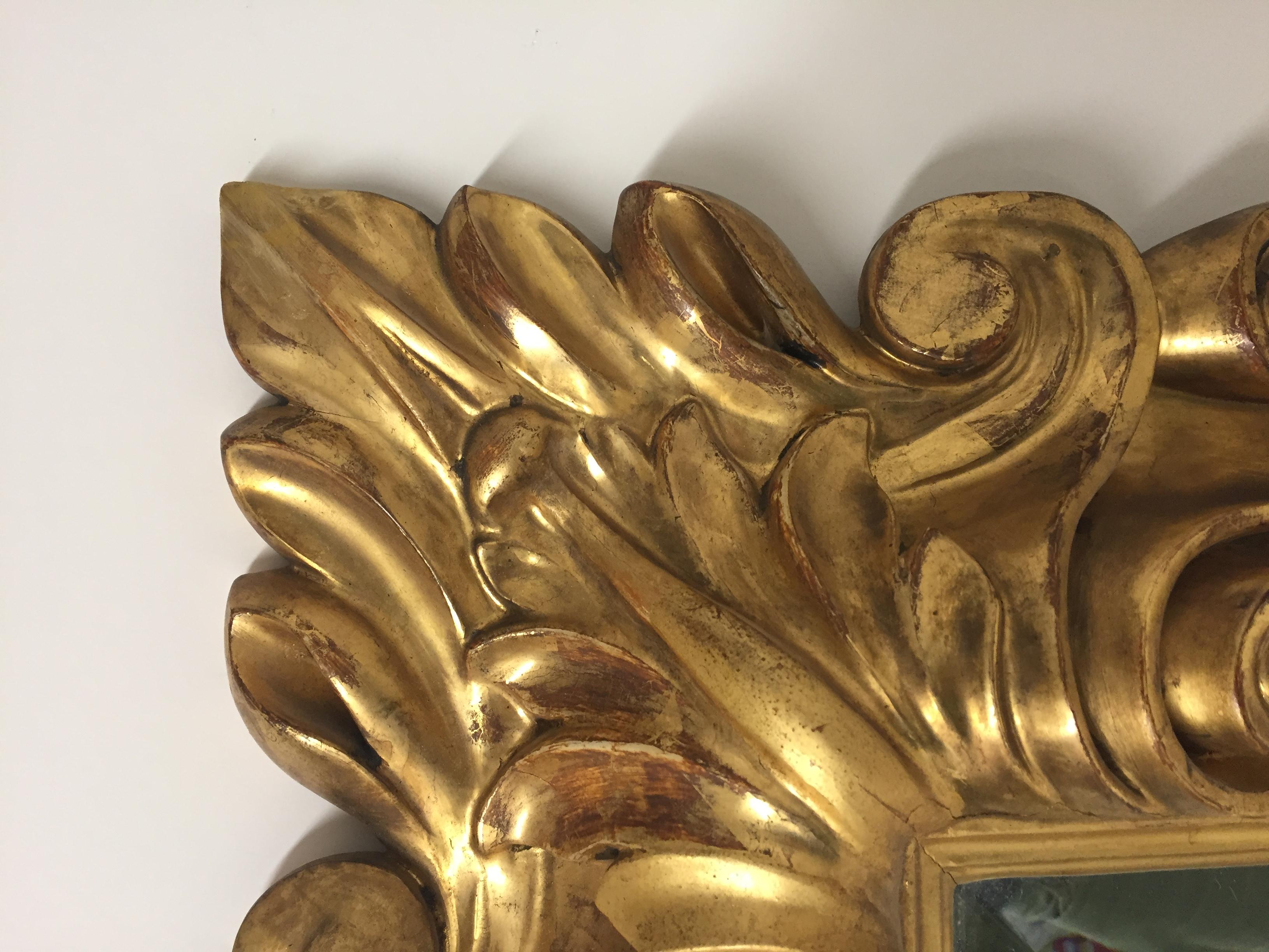 A beautiful Italian elaborately carved gilt wood mirror with 22-carat gold leaf having swirls and curlicues that are fabulous.