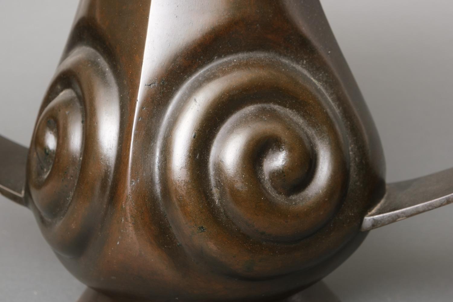 Fantastically shaped large Japanese bronze mimikuchi (ear-mouth) flying handle vase. The vase has two large flat handles smoothly running into the mouth, its body has four sides and each side is decorated with a spiral in relief. With very nice