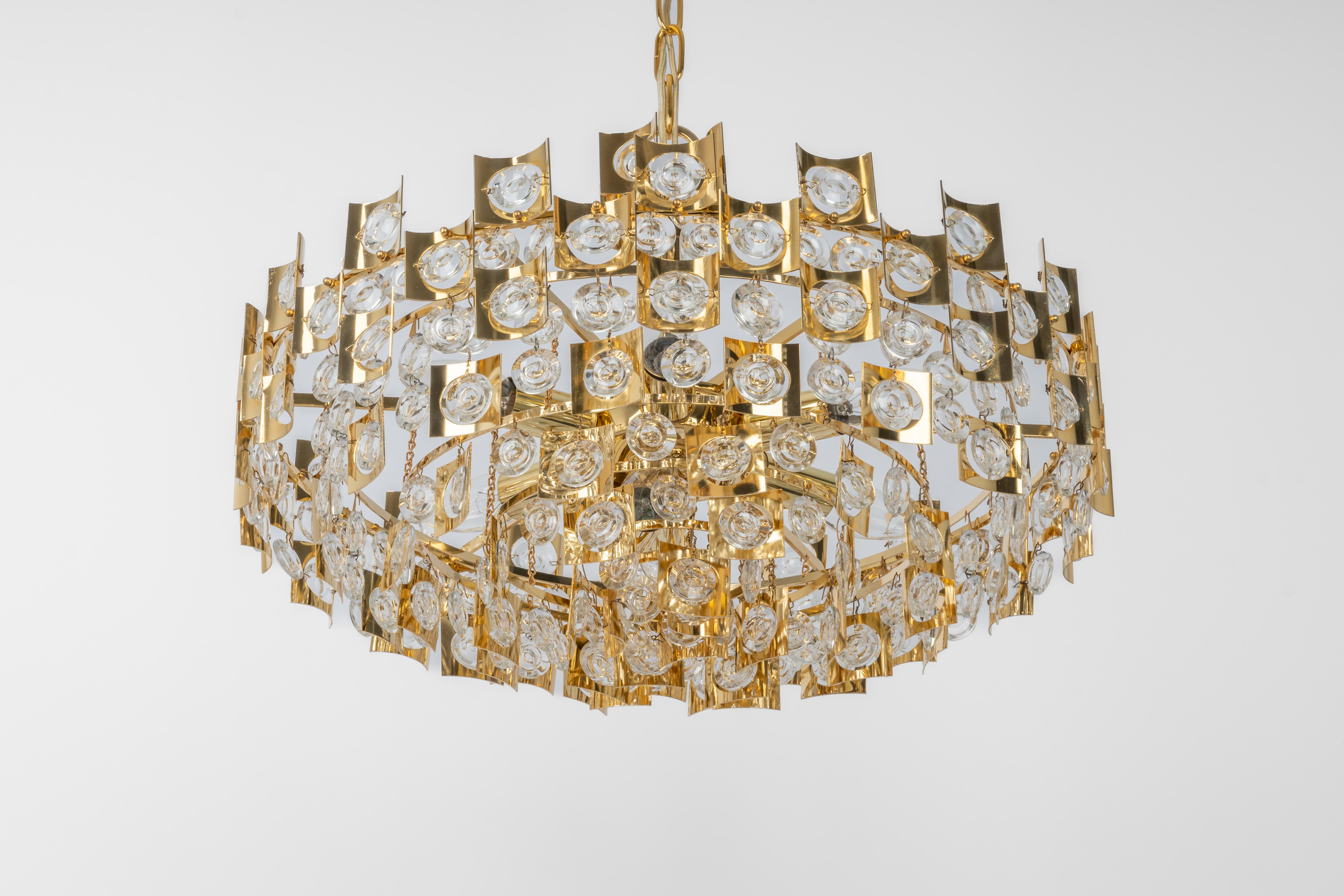 A stunning chandelier by Palwa (Palme and Walter), Germany, manufactured in the 1960s. It’s composed of jewel-like glass pieces and brass plates with a nice relief.

Sockets: It needs 7 x E14 small bulbs to illuminate.
Light bulbs are not