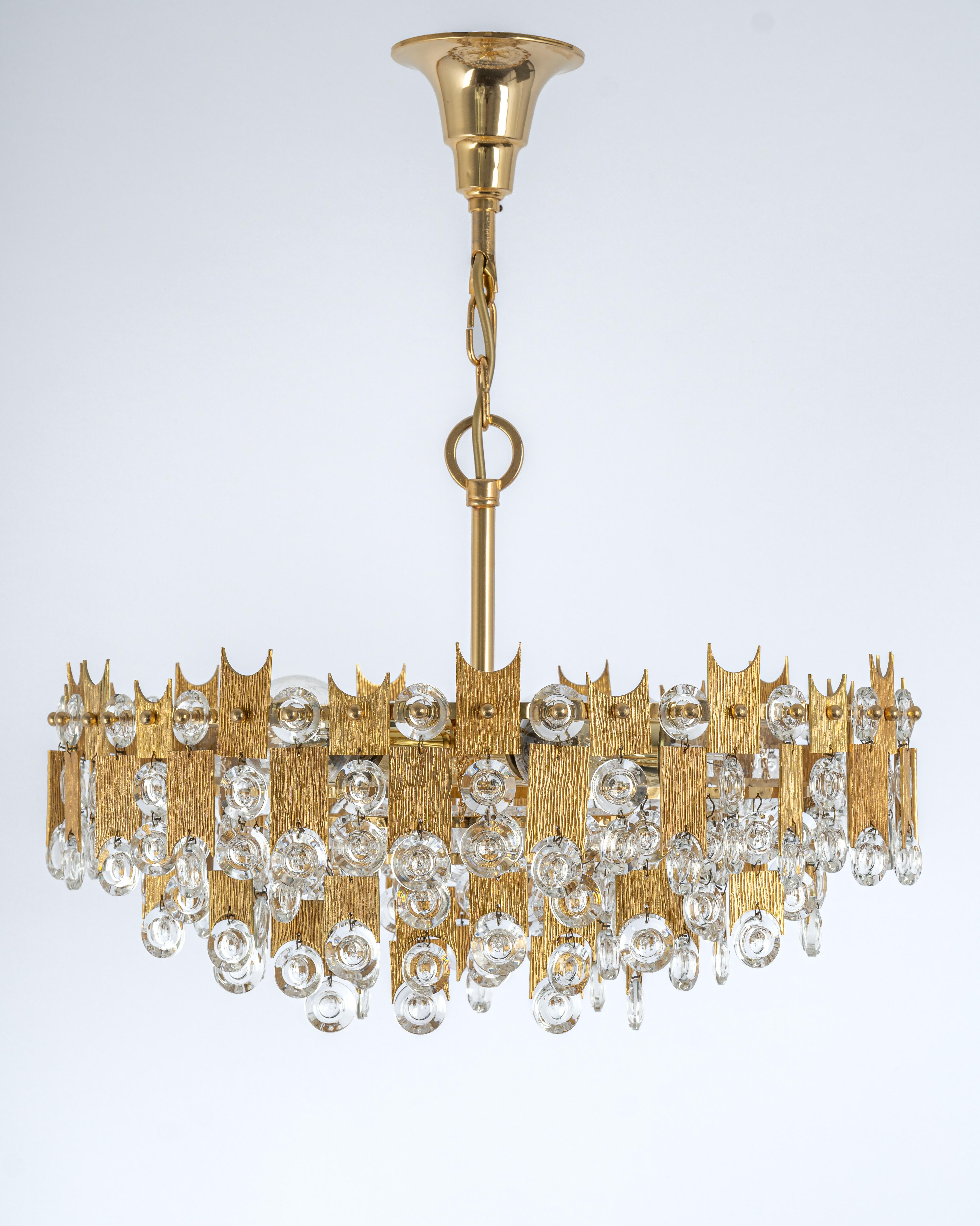 A stunning chandelier by Palwa (Palme and Walter), Germany, manufactured in the 1960s. It’s composed of jewel-like glass pieces and brass plates with a nice relief.

Sockets: It needs six x E27 standard bulbs to illuminate.
Light bulbs are not