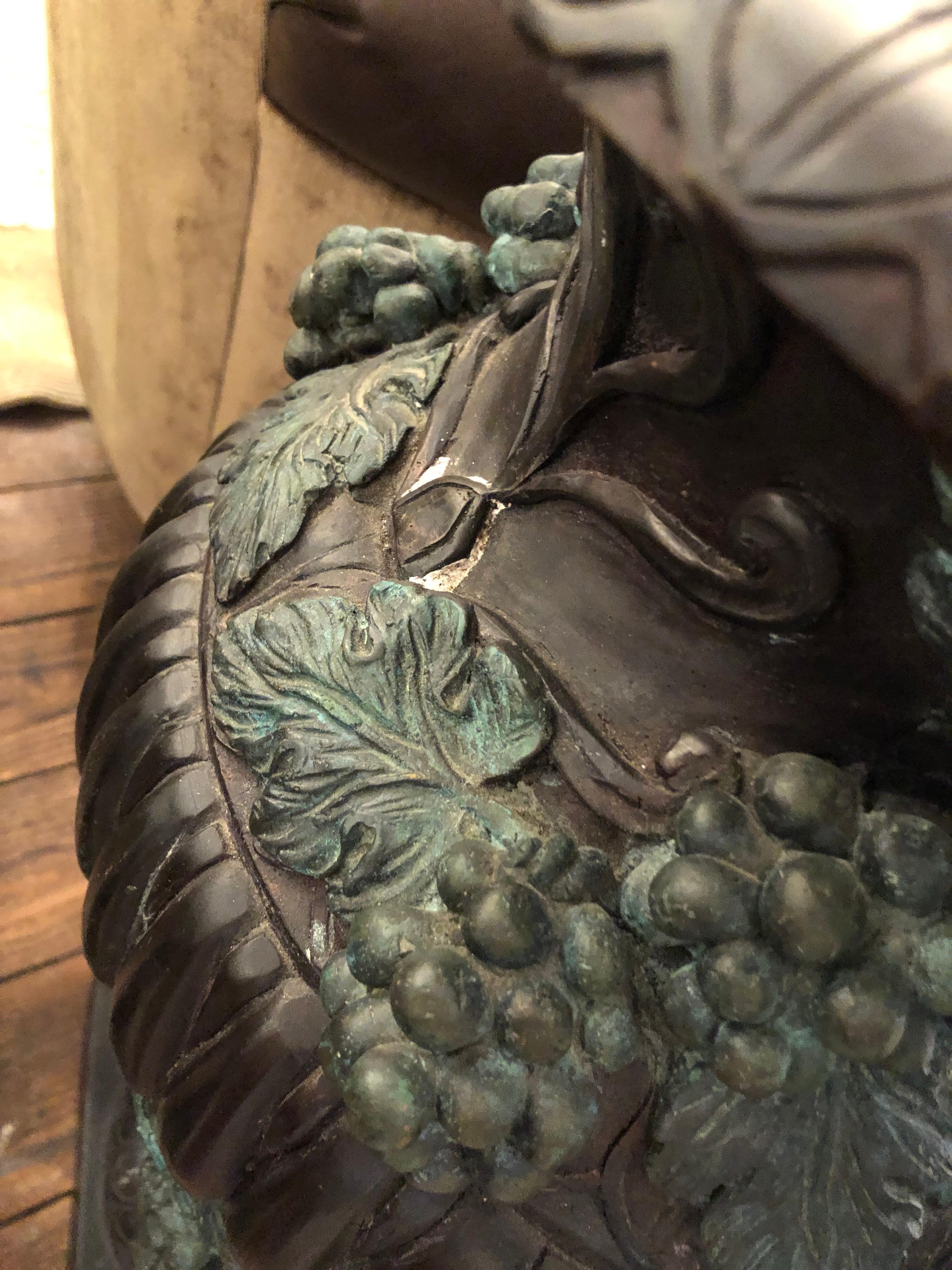 Impressive ornate and large bronze urn having a blackened matte finish with some verdigris coloration.  There is a removeable lid topped with acorn finial.  Gorgeous grape and leaf decorations adorn the urn as well as handles.  Base is 10