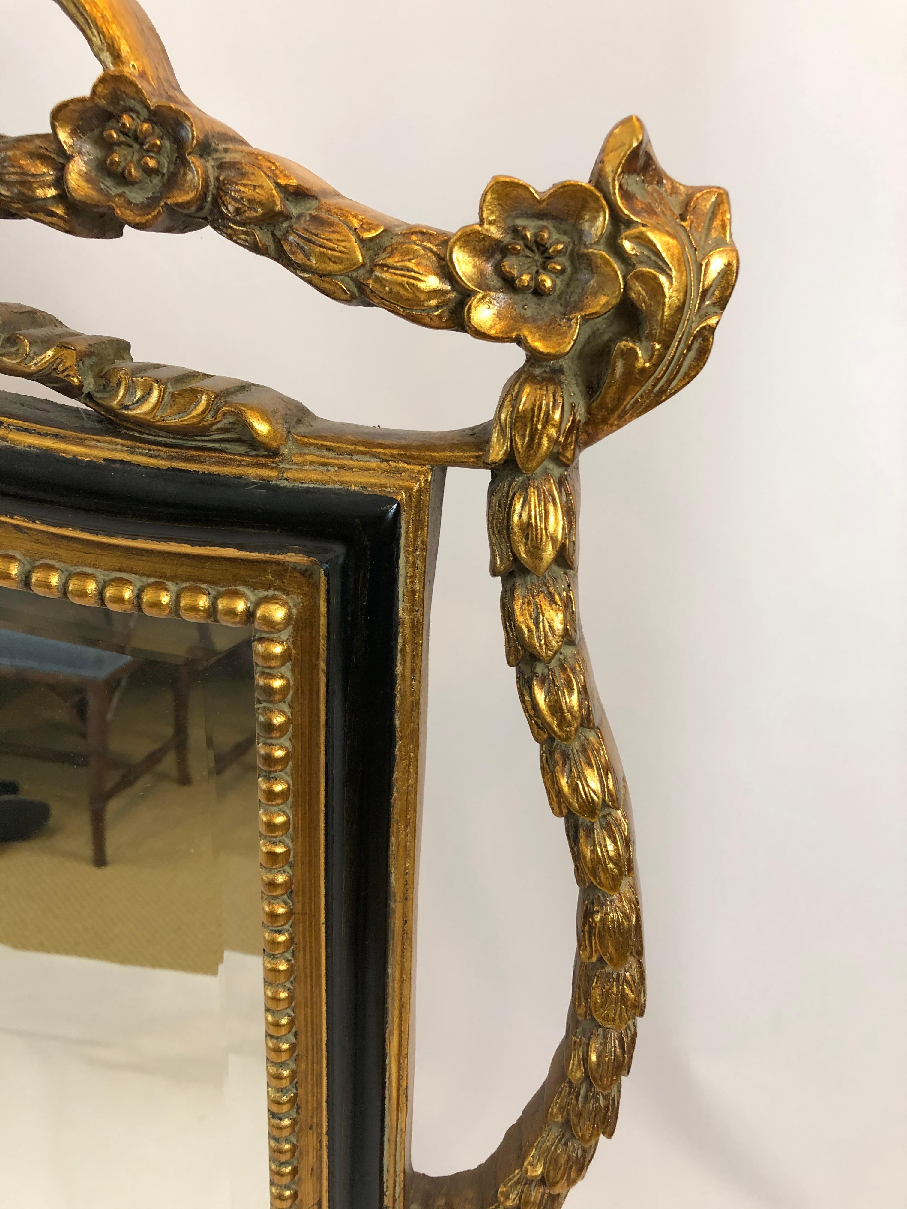 Very large beautiful mantle or buffet mirror in black and gold having lovely curlicues on top with flowers and beading around the frame.