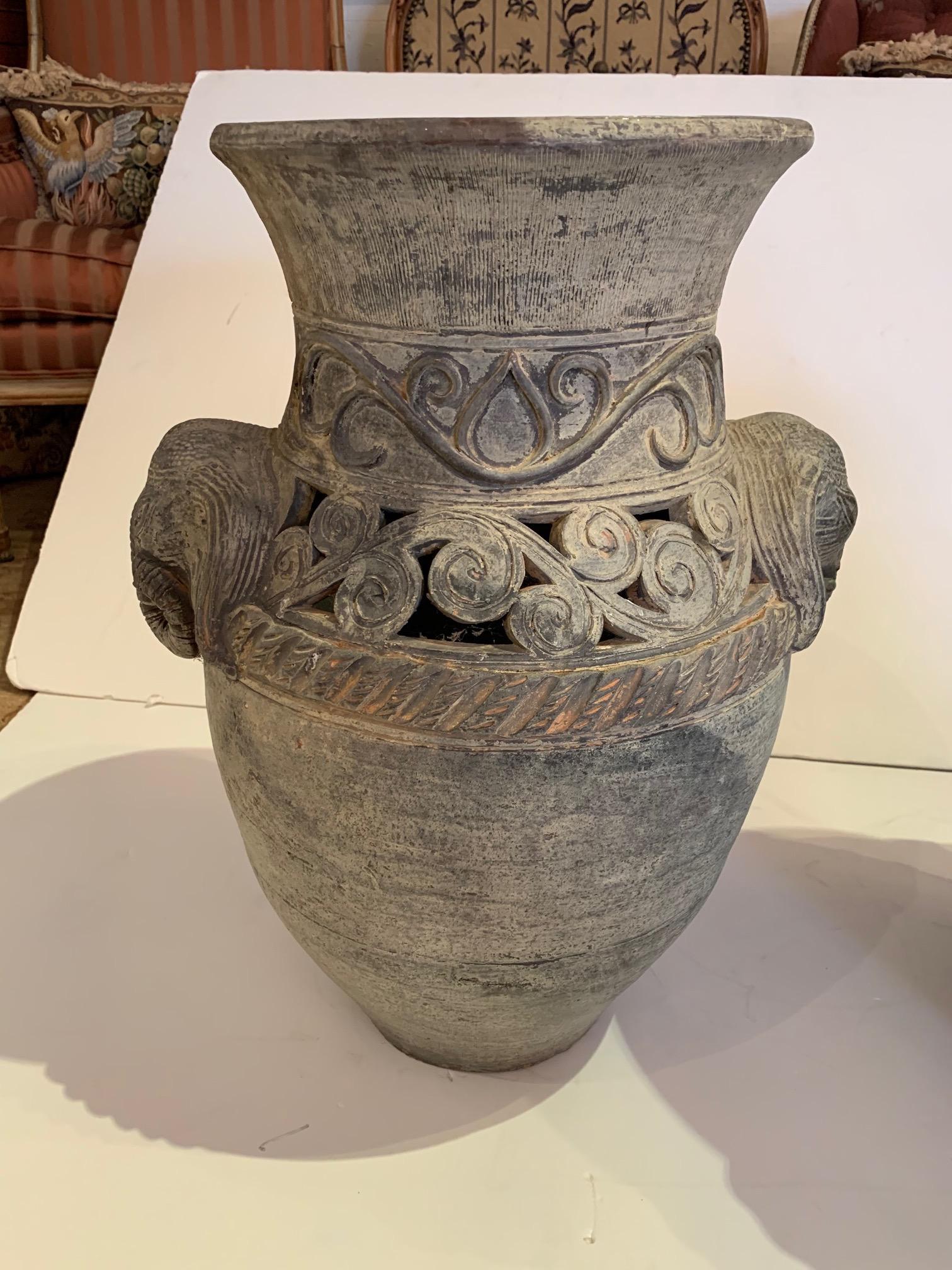 Pair of large terracotta vessels having a greyish green patina, decorated with marvelous elephant heads on the sides. One urn is slightly taller by one inch (24