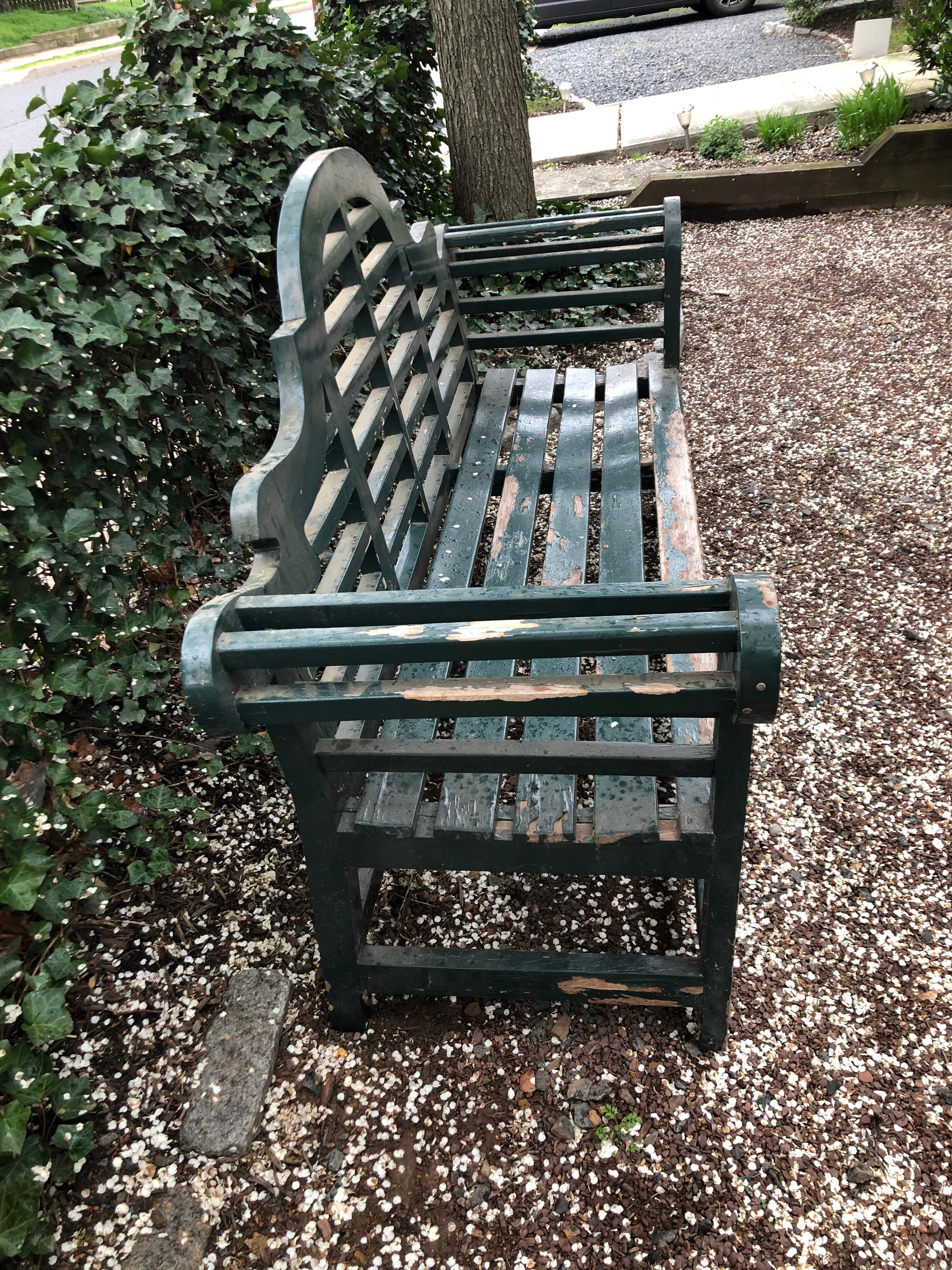 A classical Edwardian style teak bench, originally designed by the famous English architect Sir Edwin Lutyens in the early 1900s. Big, with heavy solid construction, in very sturdy condition, with chippy dark green paint. Great bones, but worthy of