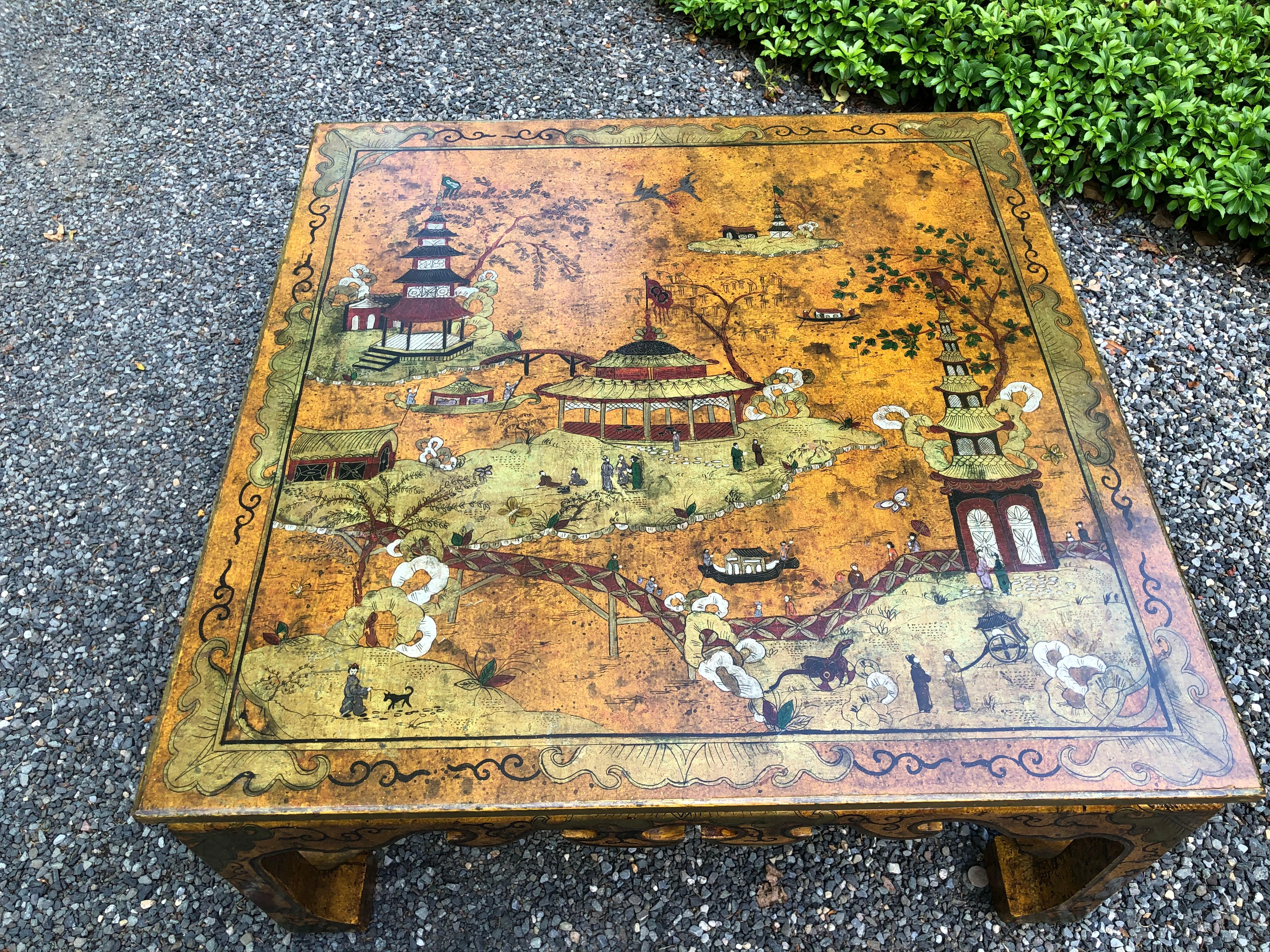 Stunning vintage chinoiserie coffee table in a deep shade of ochre. Asian scenes include temples, pagodas and landscapes and have been hand painted on the surface of the table in various shades of red, green and black. The apron and legs of the