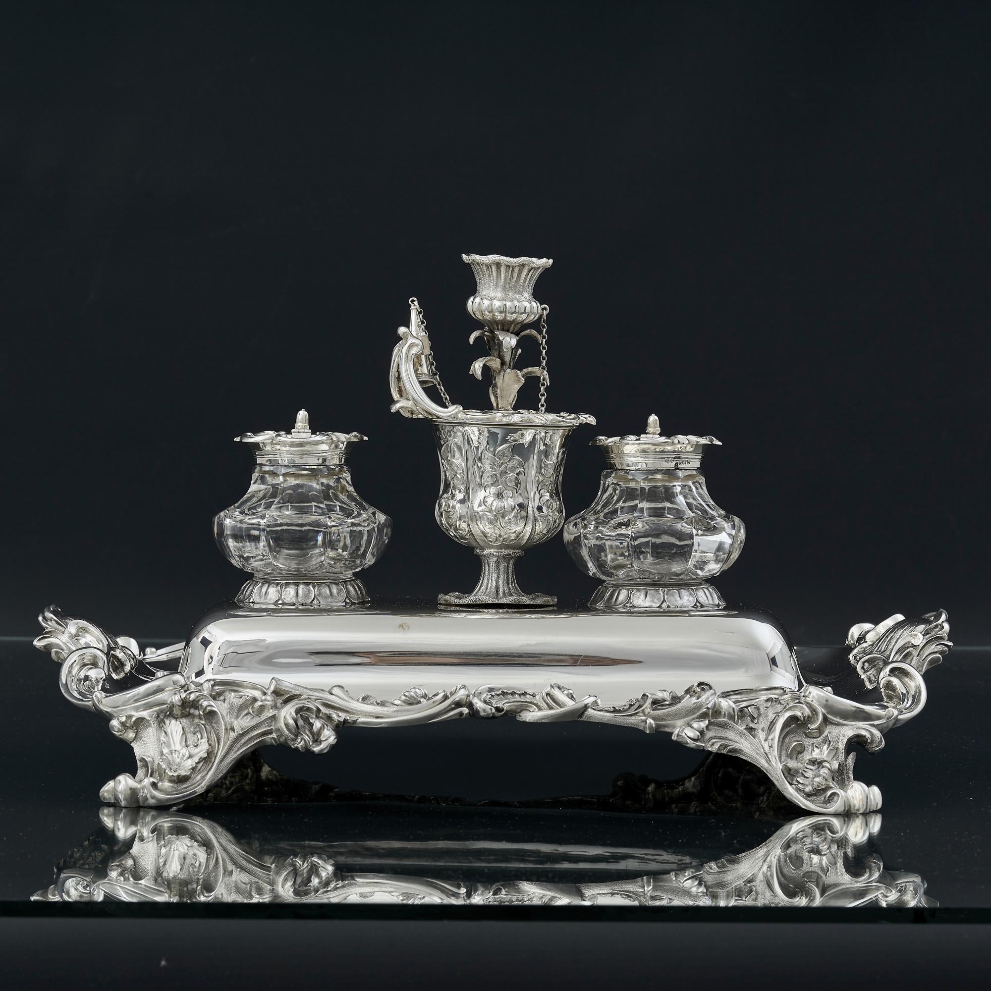 Antique silver inkstand of impressive proportions, made at the end of King William IV's reign. The inkstand has finely detailed scroll and leaf pattern cast mounts and rets on four scroll leaf and flower supports. 

Both inkwells are fitted with