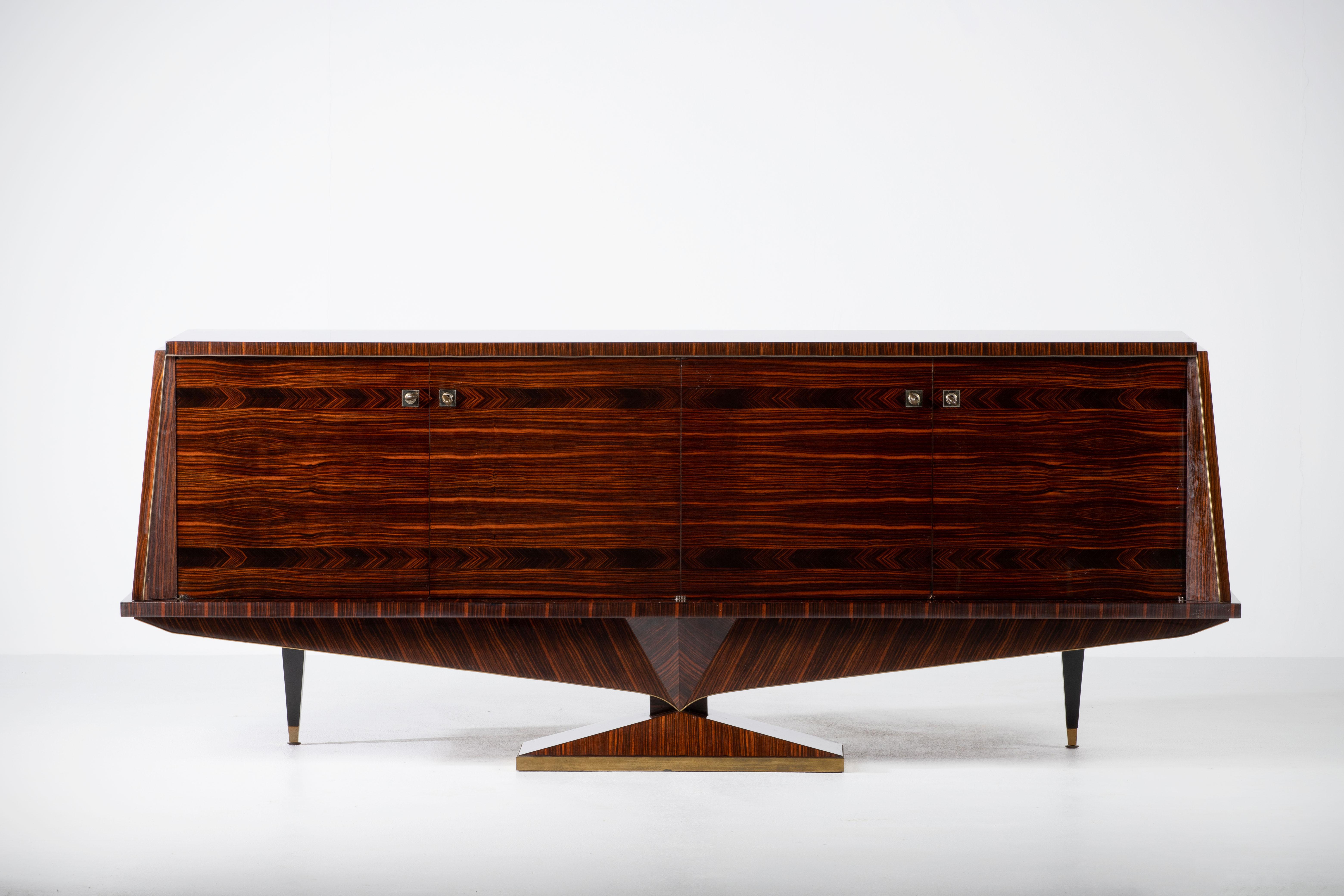 Impressive Macassar sideboard, France, 1960s.
The sideboard features stunning design, Macassar wood grain and rich pattern. 
It offers ample storage, with shelves and a column of drawers. 
The case rests on a central diamond shaped leg with brass