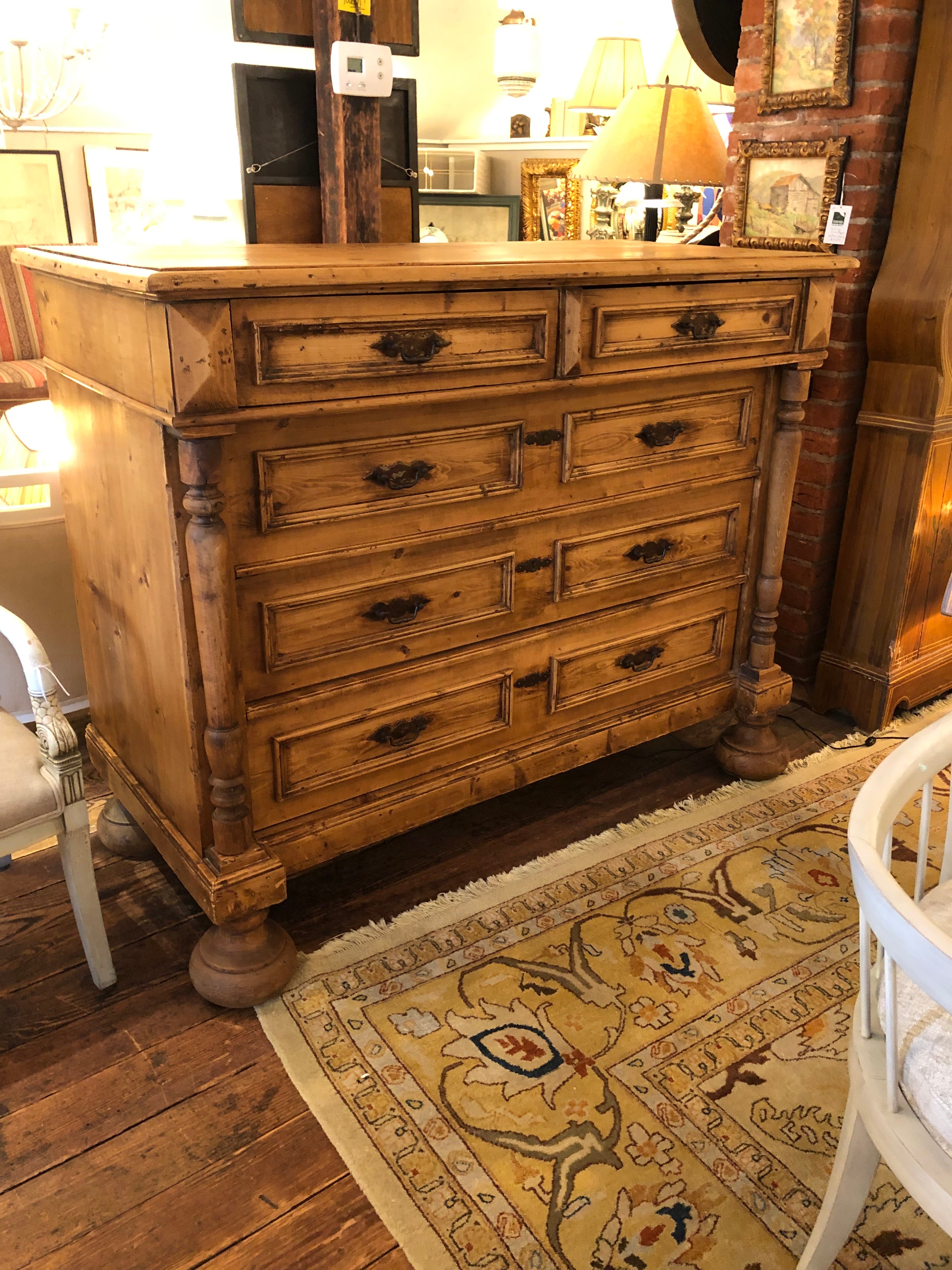 A rare and impressive carved natural pine chest of drawers having two smaller drawers on top of 3 very large drawers, original matte bronze finish hardware, and fabulously massive bun feet. Beautiful grain and honey warm weathered patina. 