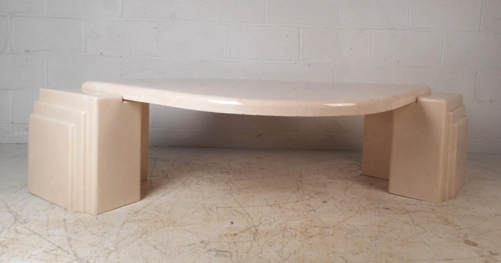 This gorgeous vintage modern coffee table features a uniquely shaped top with two sculptural supports on each side. The unusual tear drop shaped table top and beautiful off-white color adds to the allure. A sleek design that is sure to make a