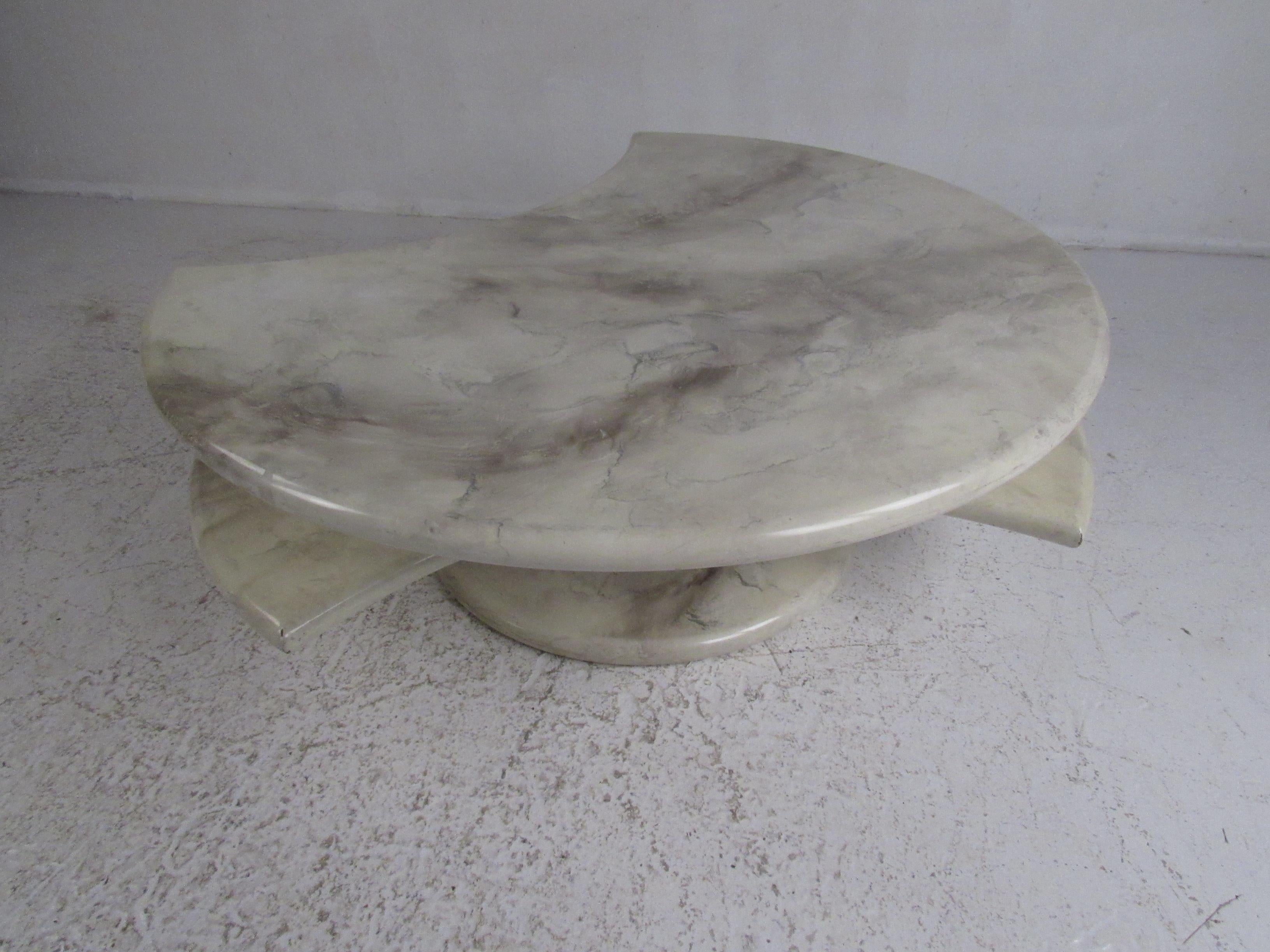 An unusual vintage modern two tier coffee table with a swivel top. The sleek design swivels outward unveiling a lower tier to set items on. A unique half moon shape, beautiful faux finish, and sturdy base make this cocktail table the perfect