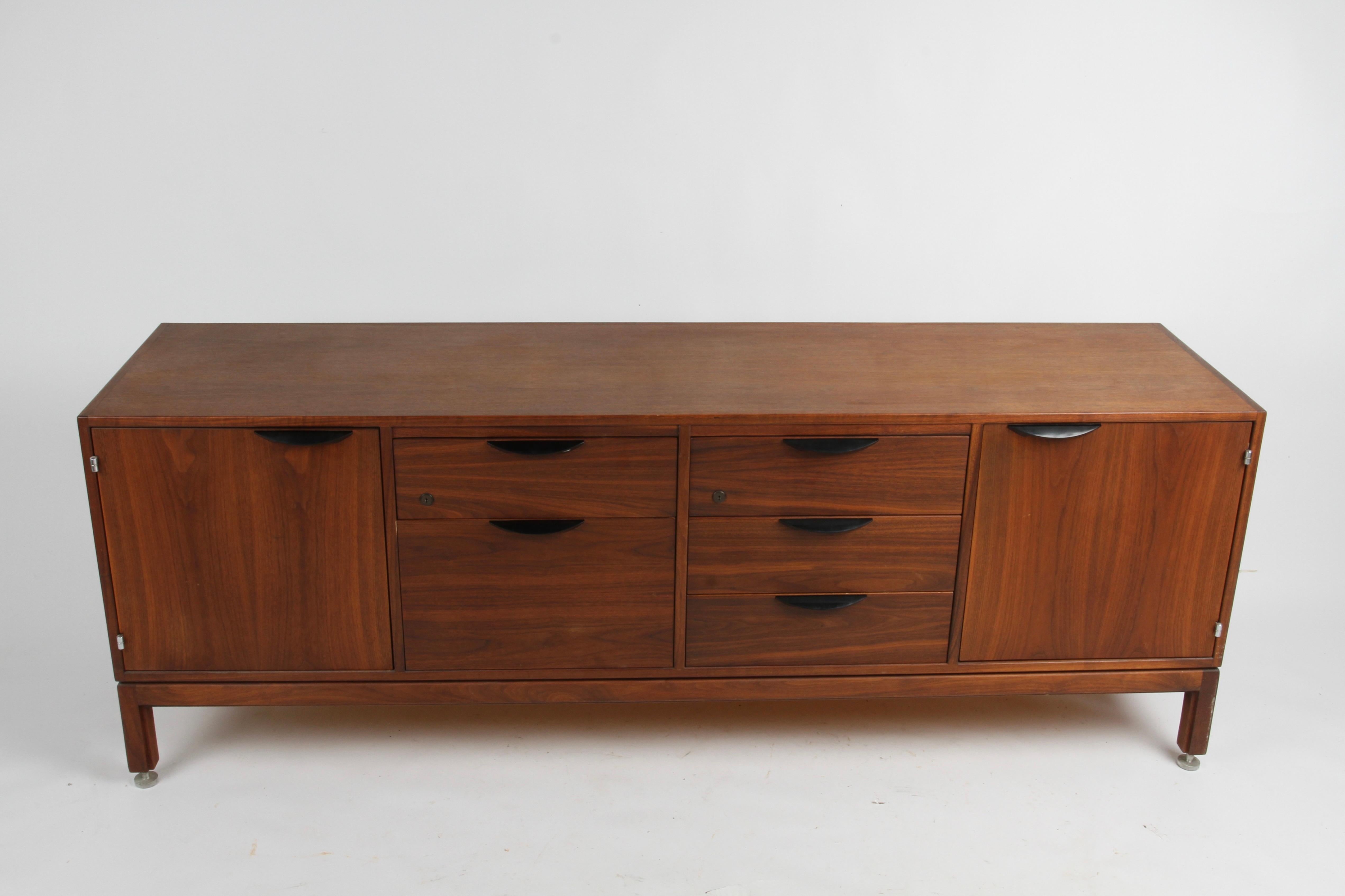 Handsome Jens Risom (1916-2016) designed Danish Modern walnut credenza is perfect for office or home. Designed and produced by Jens Risom Inc in the late 1950s or early 1960s. The richly grained walnut case comprises of two cabinets with adjustable