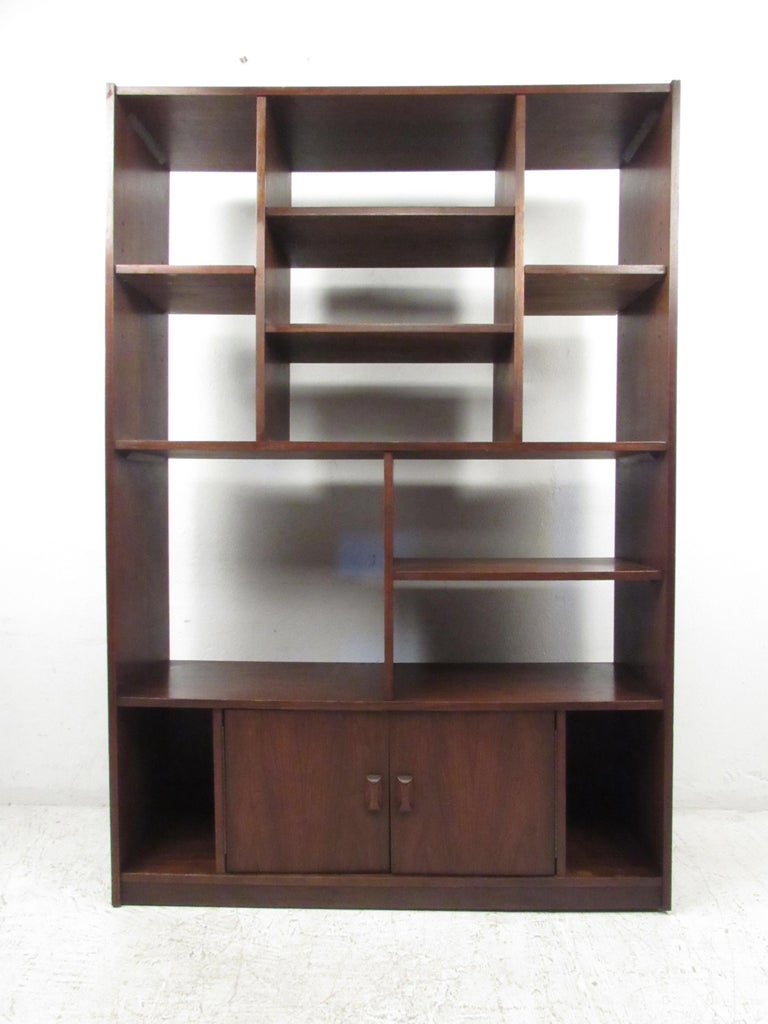 This stunning vintage modern wall unit features thirteen compartments for storage and display. A stylish and functional bookcase that features cabinet doors on the bottom with carved pulls and adjustable shelves. This beautiful mid-century case