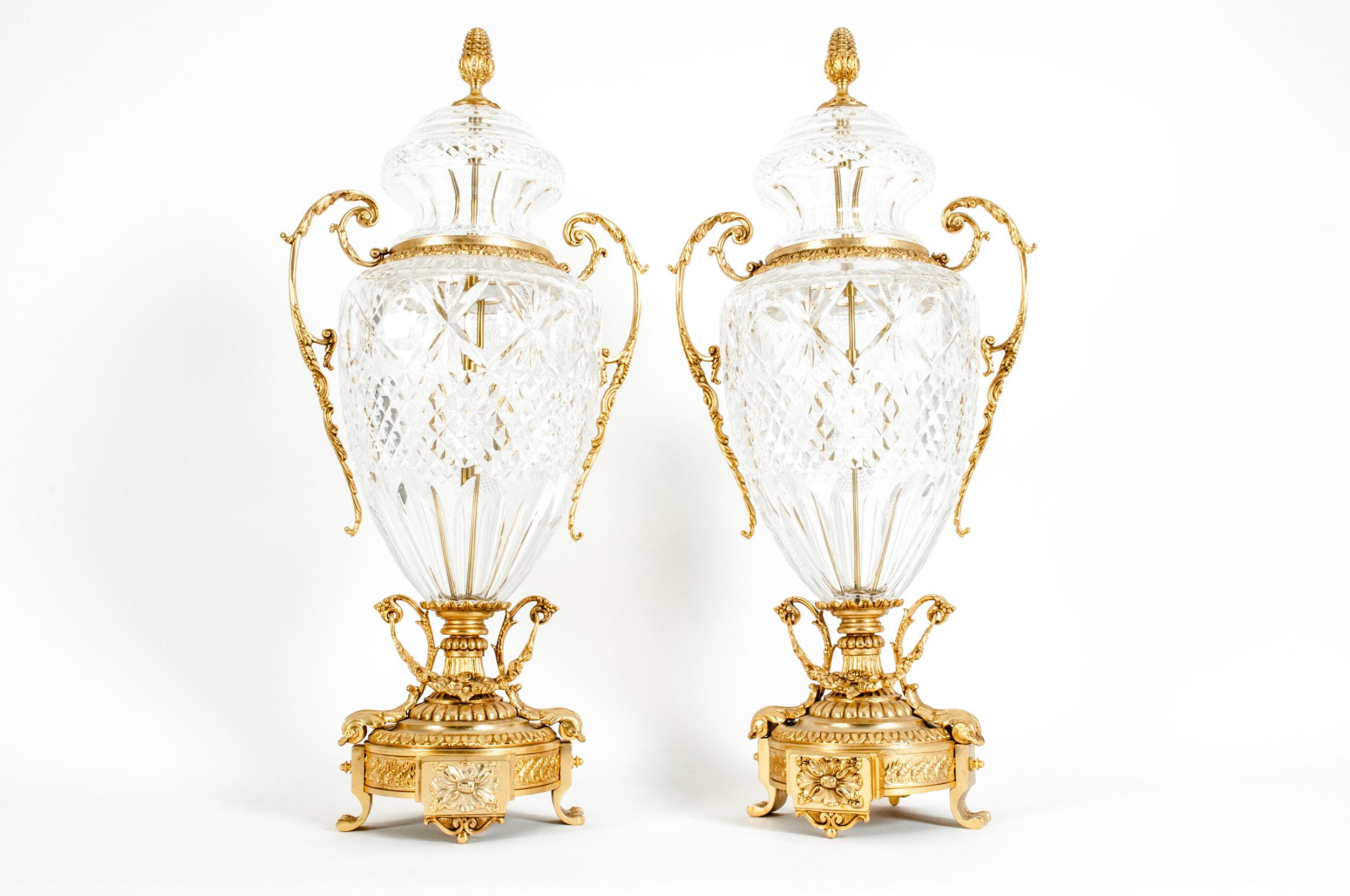 Impressive pair of footed gilt bronze-mounted diamond shape cut crystal decorative urns / centerpiece. Each urn is mounted on a squared base, flanked by two scroll gilt handles with exterior design details , finished with an acorn finial all the way