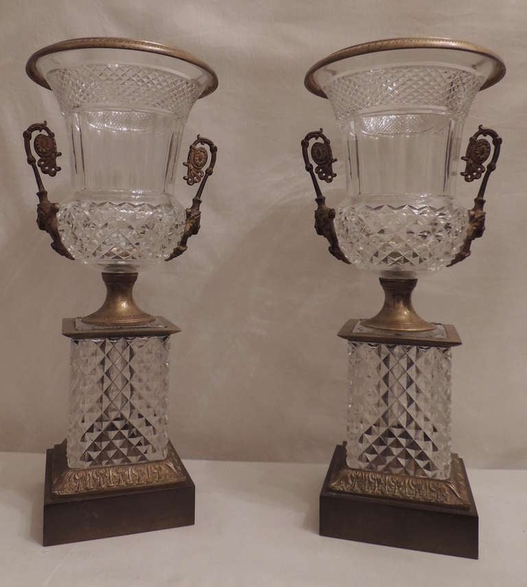 An impressive pair of French cut crystal and doré bronze ormolu-mounted urns featuring figural handles.