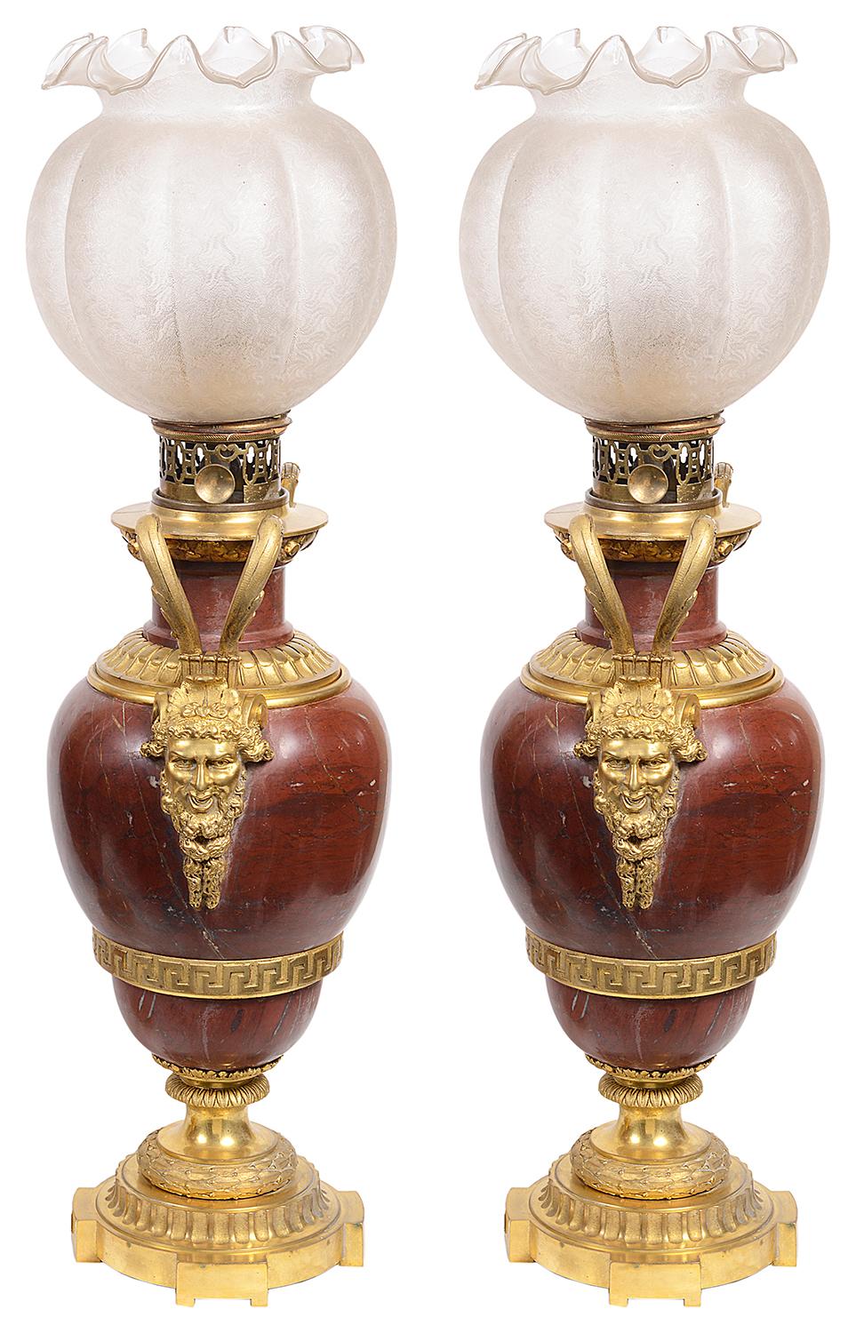 A very impressive pair of 19th century French classical oil lamps, each with their original scalloped glass shades, wonderful gilded ormolu scrolling handles coming down to the beard mask mounts on either side. The rouge marble body with Greek key