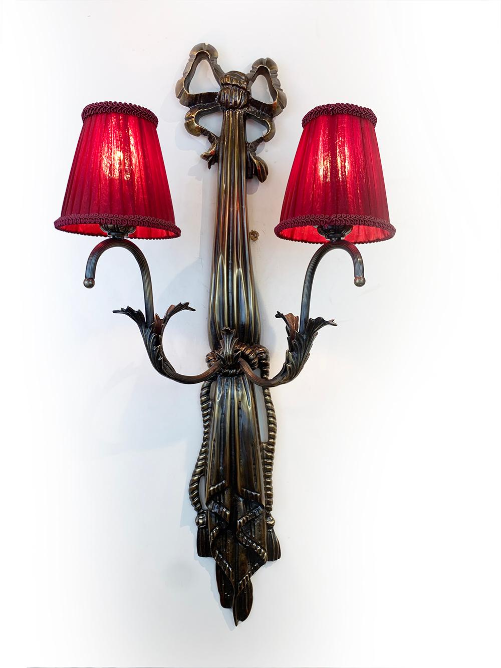 Pair of French Art Deco wall lights consists of a vertical bronze structure having beautiful motif design with two curved arms of lights supporting two pleated “bistro” shape lampshades in dark red linen fabric. Lovely when the lights on.
Each item