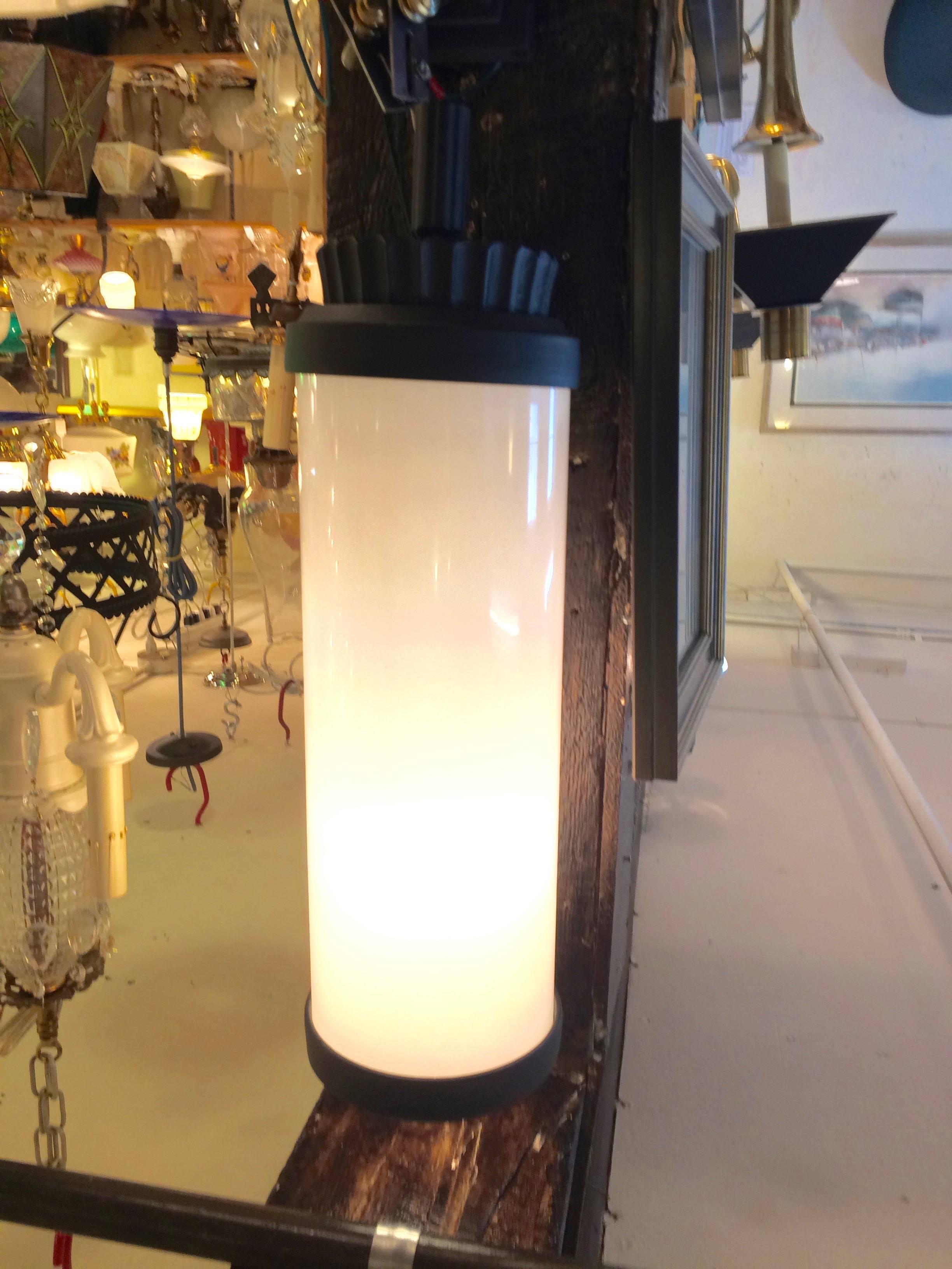 Sensational large pair of column shaped sconces having black metal wall plate and handsome designed top and bottom on each milk glass tube. Can be hung in either direction. The side with no decoration is open, so if used outdoors, would need to be