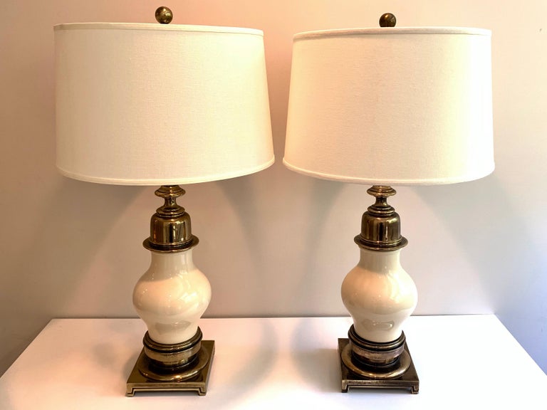 Pair of large and impressive table lamps in ivory ceramic with solid aged brass base and accents by Stiffel Lighting, American, 1950s. Double cluster socket, labeled 
