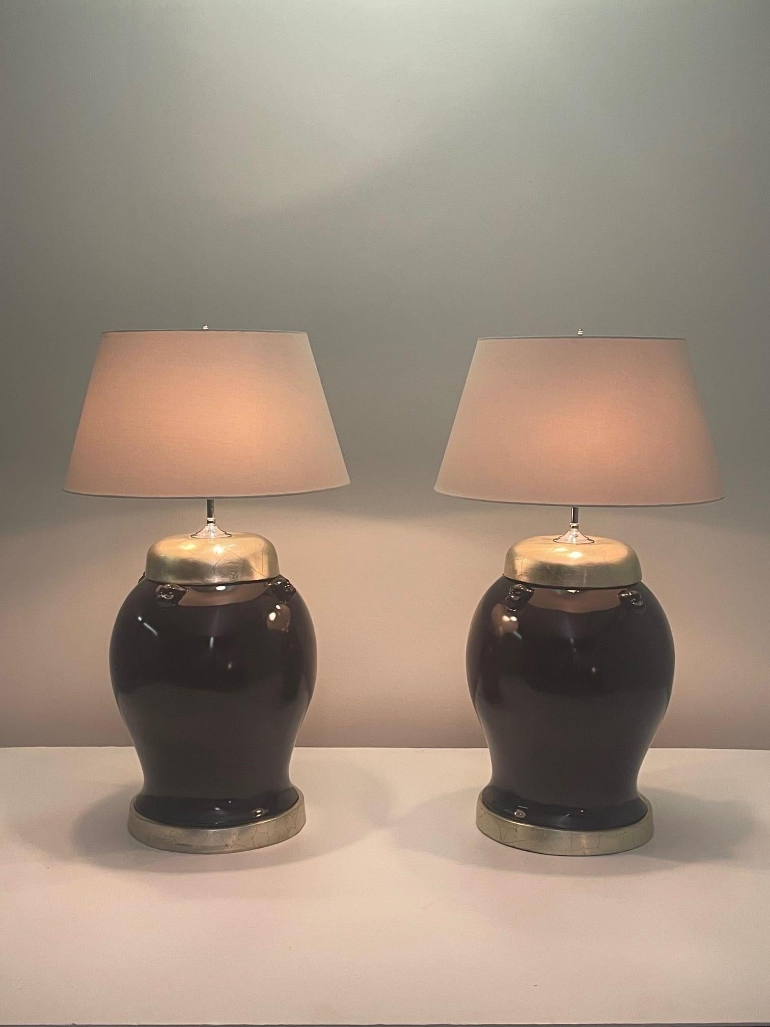 Glamorous Italian ceramic ginger jar shaped table lamps in a stunning burgundy lacquer complimented by silver leaf tops and bases. The embossed foo dog decorations add an exotic touch.
Shades not included.