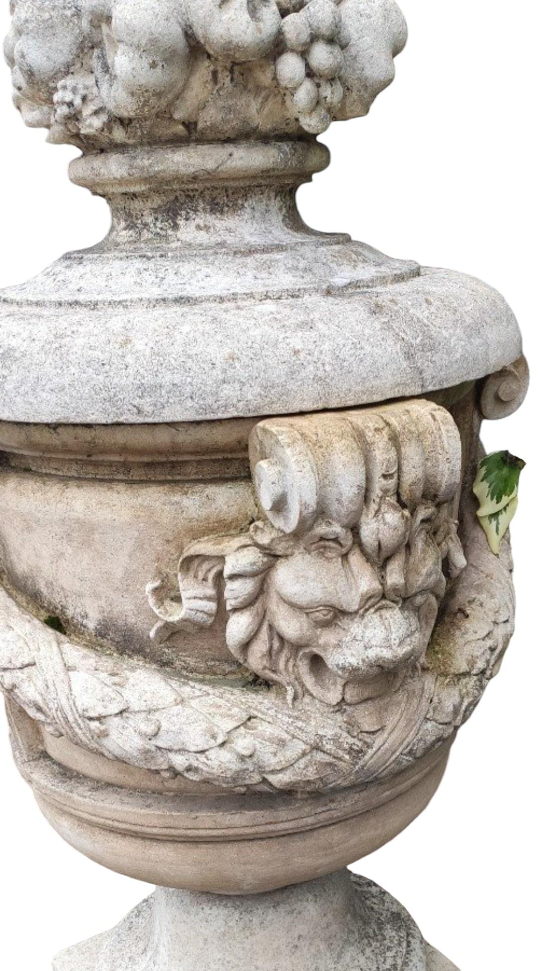 Introducing a magnificent pair of stone vases from the 1950s, each standing at an impressive 157 cm (5.15 feet) tall. These vases are adorned with intricate lion heads and floral garlands, embodying the elegance and grandeur of mid-20th-century