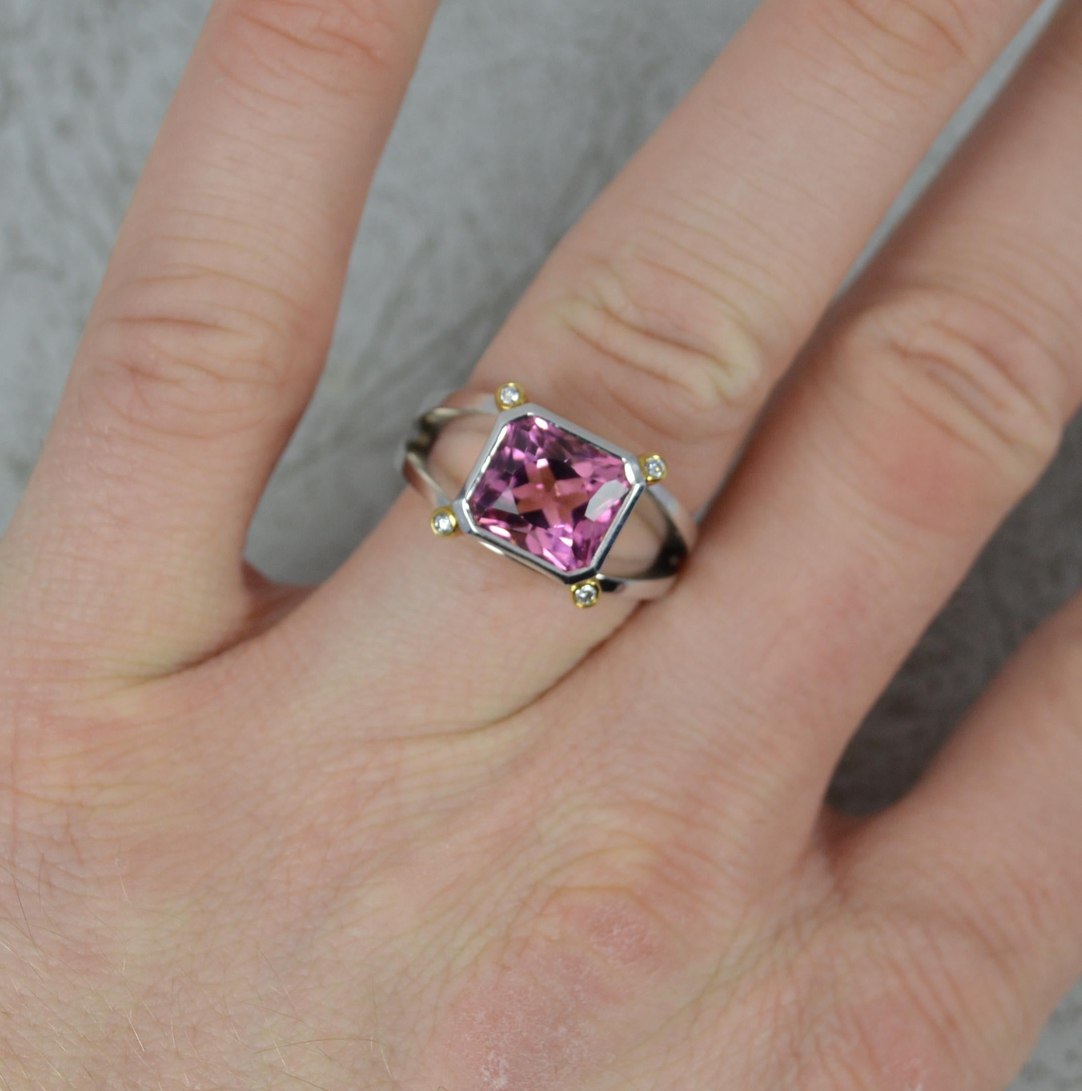 A superb contemporary cluster ring.
Solid 18 carat white gold example with yellow gold bars holding the diamonds in full bezels.
Designed with a cushion cut vivid pink tourmaline to centre. 9.1mm x 8.4mm approx. Set with a small round brilliant cut