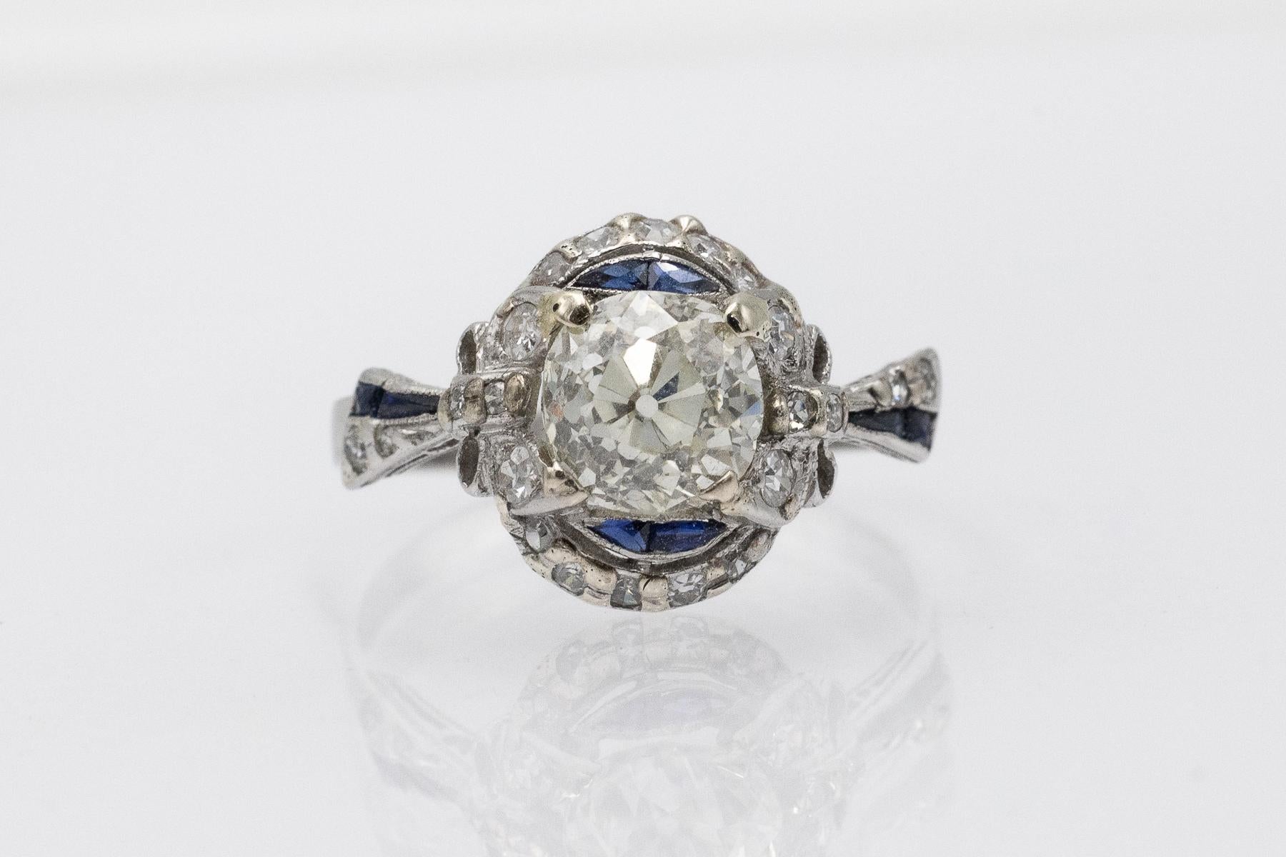 Este anillo único está elaborado con oro blanco de 14 quilates (0,585 de ley) y platino (0,950 de ley). Su pieza central es un impresionante diamante talla brillante antiguo de 1,74 ct (color K, claridad SI1). También presenta 21 diamantes talla 8/8