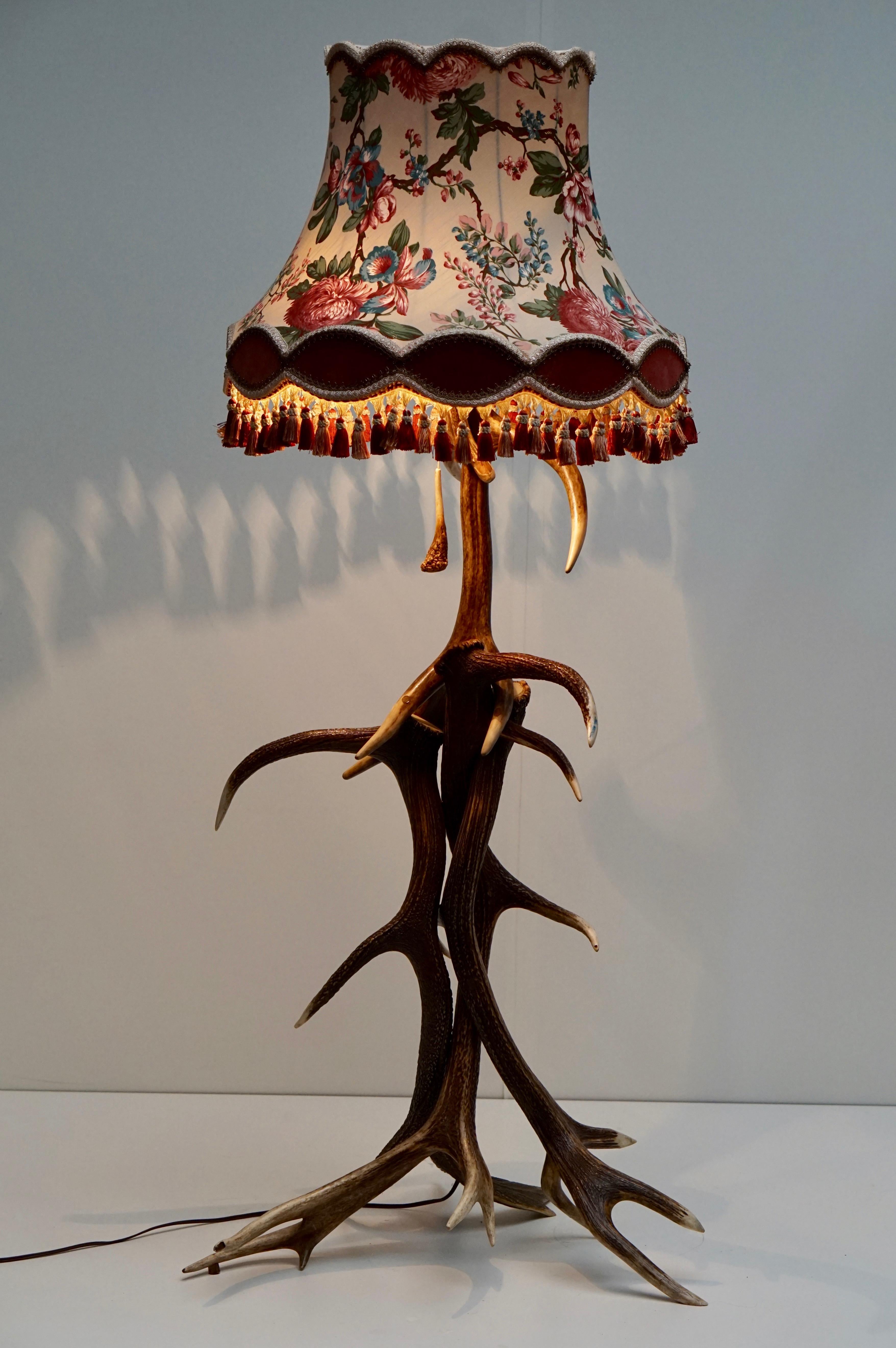 Very impressive deer antler floor lamp handmade in 1950s in Austria. The lamp is made of discarded deer antler. 
The very beautiful original 1950s shade color is Bordeaux and decorated with flowers. 
The lamp is in excellent condition. Fully