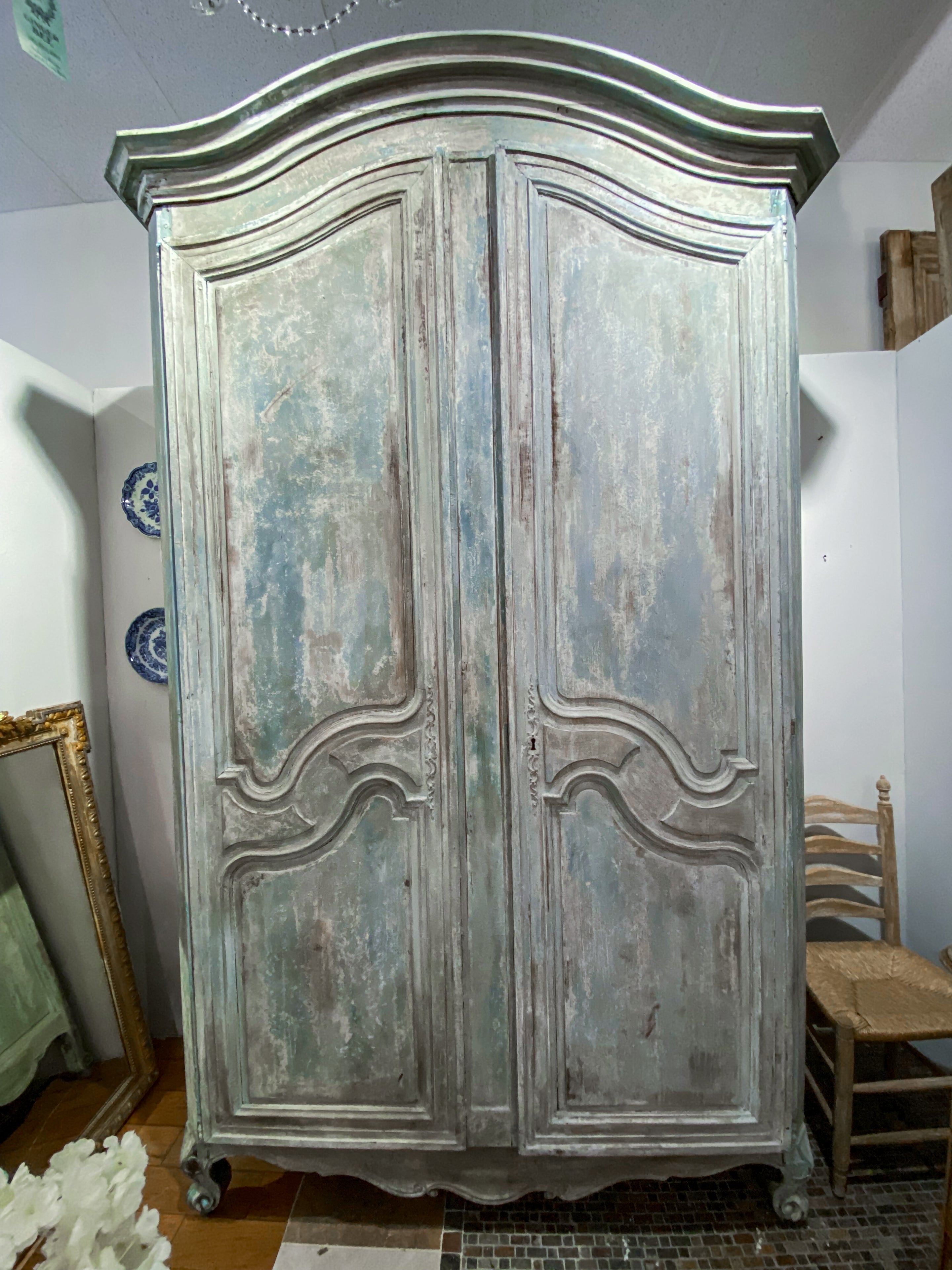 The Impressive Scale 19th Century Louis XV Style Painted Armoire is a remarkable furniture piece that reflects the elegance and sophistication of the Louis XV era. The armoire features shaped paneled doors, adding a touch of artistic flair to its