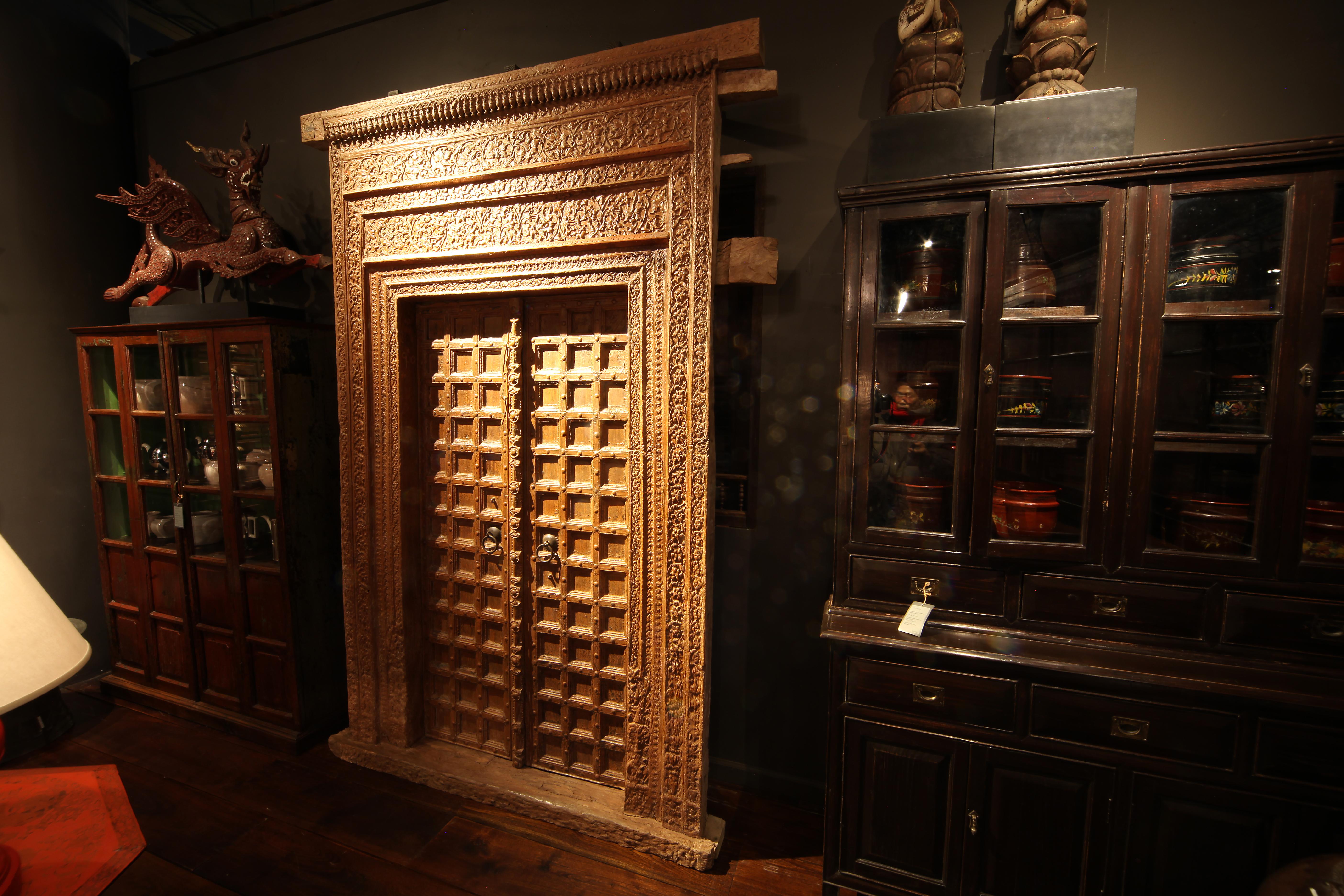 Diese monumentale geschnitzte indische Eingangstür ist aus Chechum-Holz gefertigt und verfügt über einen beeindruckenden und komplizierten Türrahmen. Die Rahmenelemente unmittelbar neben den Türen sind jeweils aus einem großen Stück Holz geschnitzt,