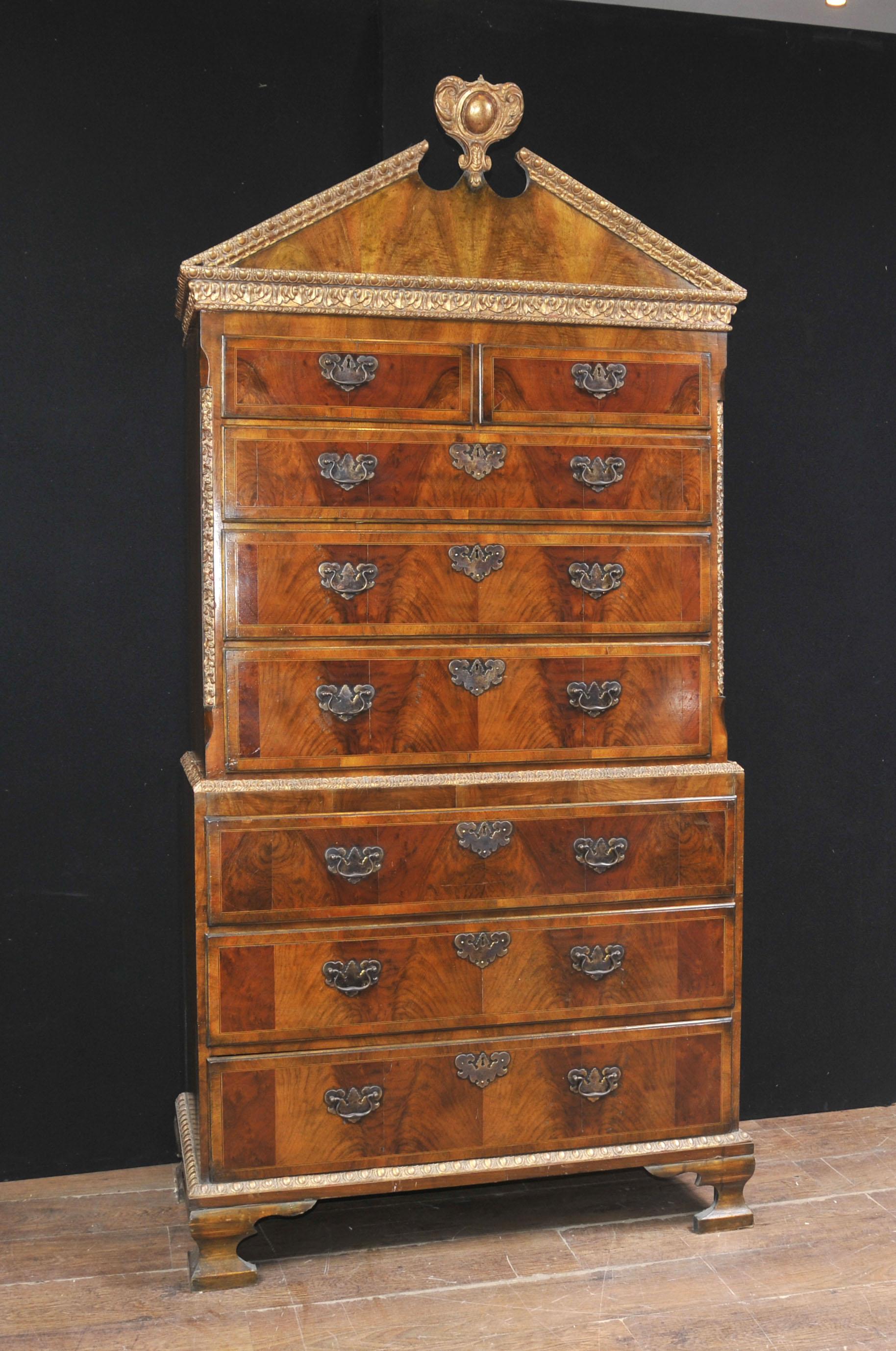 An impressive sized English burl walnut chest on chest dating to 1840 standing on ogee bracket feet, the top pediment is in a triangular form and is surmounted by a parcel-gilt motif, this parcel-gilt decoration is continued down on to the canted