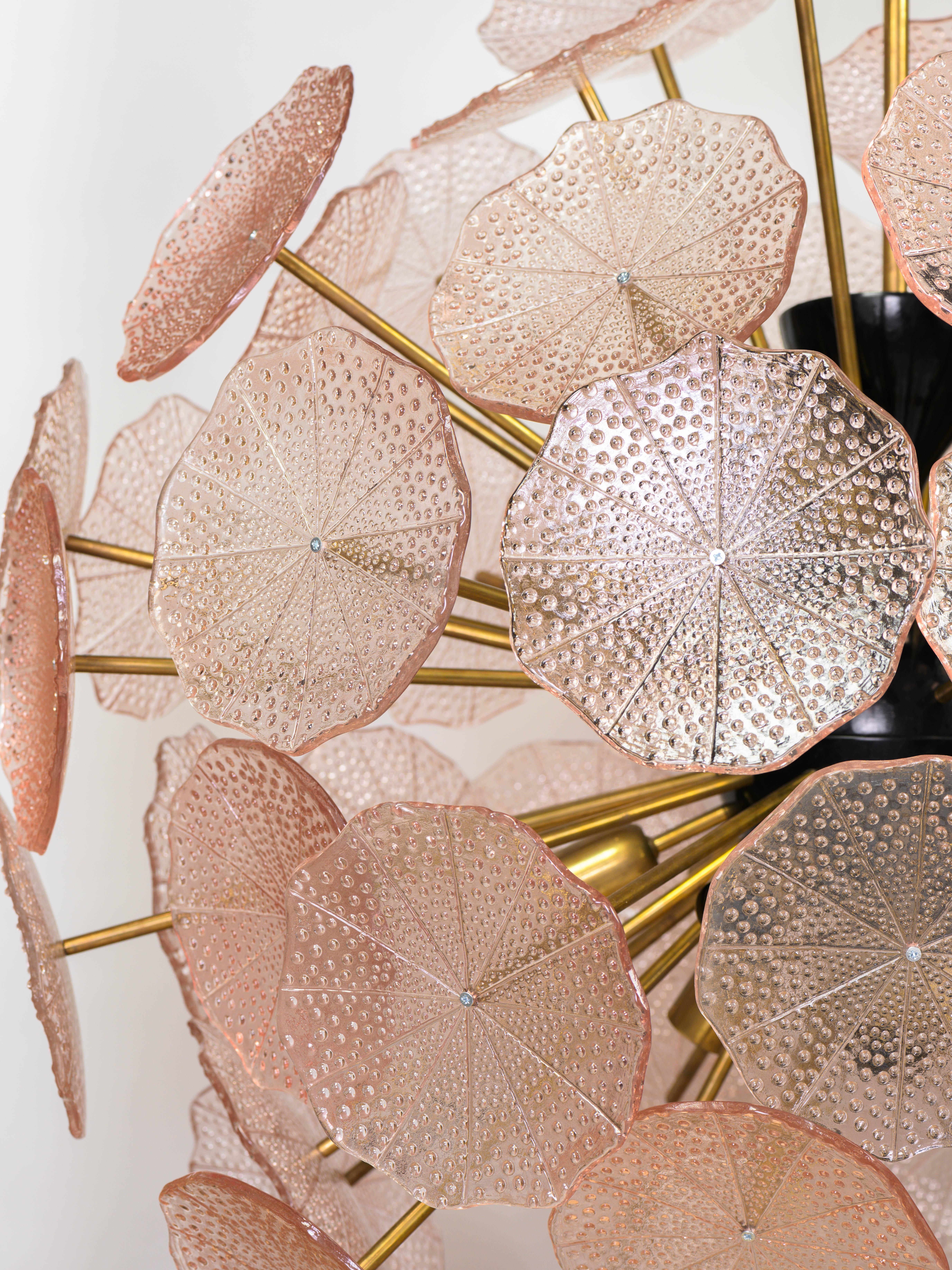 Impressionnant lustre en laiton et disques en verre de Murano en forme de fleurs roses. 

Les nombreuses portes à ampoules donnent une lumière très diffuse et confèrent une atmosphère folle à l'espace. 

Son diamètre imposant en fait un élément fort