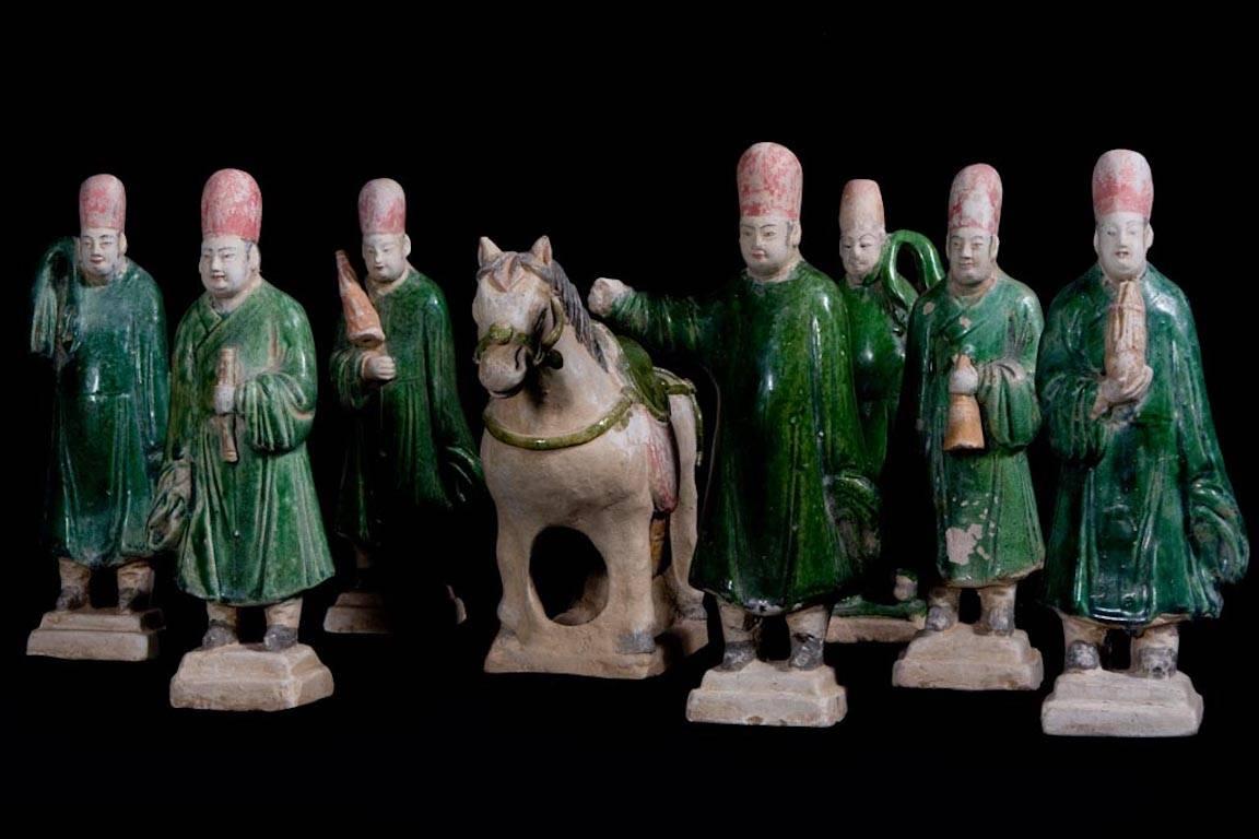 Beeindruckende Grabbeigabe von 10 Terrakotta-Figuren in Grün und Karamellfarben, die eine Votivprozession mit einer Sänfte, seinen vier Trägern, einem Pferd, einem Stallknecht, zwei Musikern und einem Opferträger darstellen. 

Dieses Ensemble wird