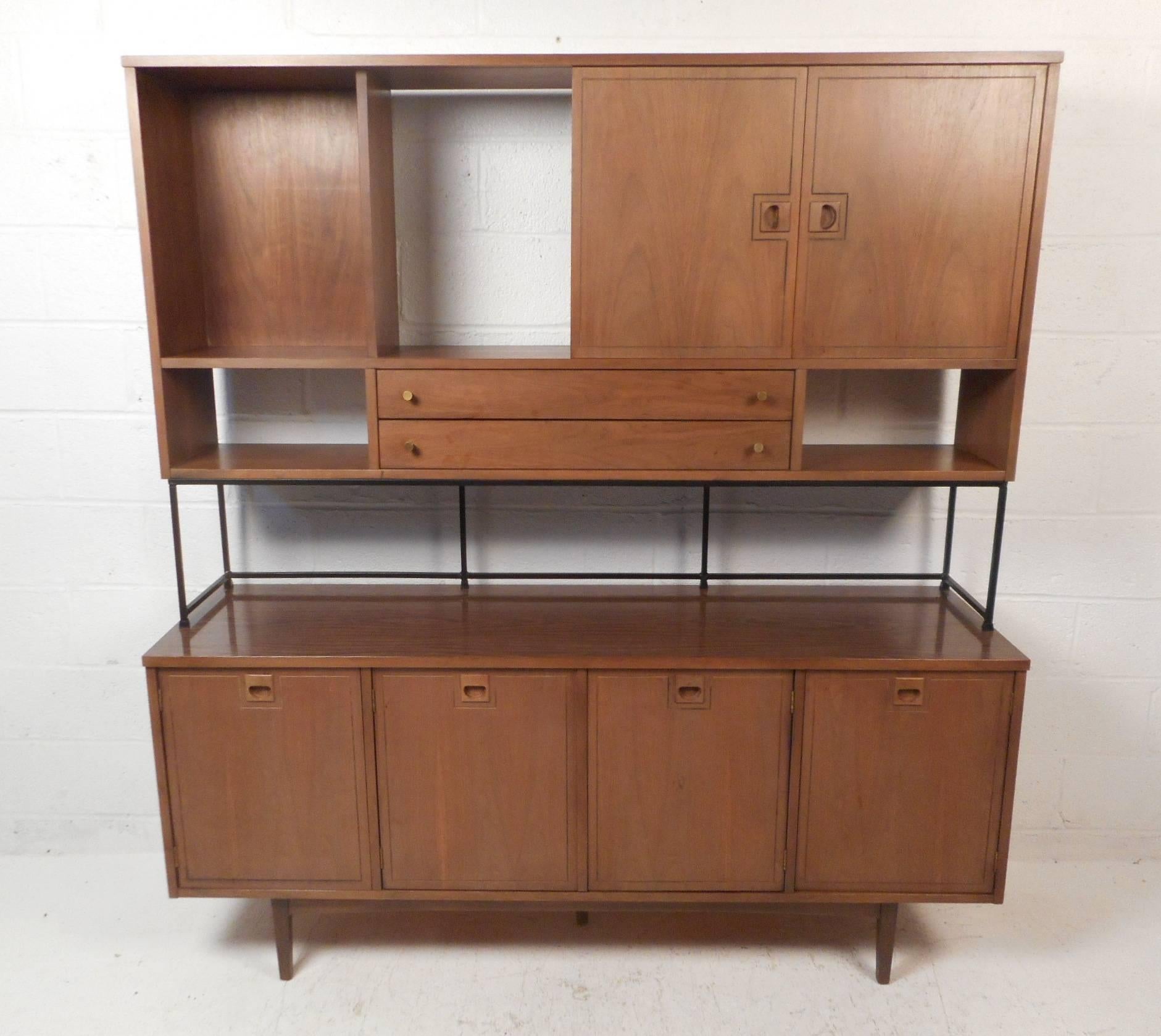 A stunning mid-century modern hutch by Stanley Furniture that consist of two separate pieces. This wonderful case piece offers ample room for storage within its many compartments and drawers. A topper with sliding doors, two drawers, and an iron